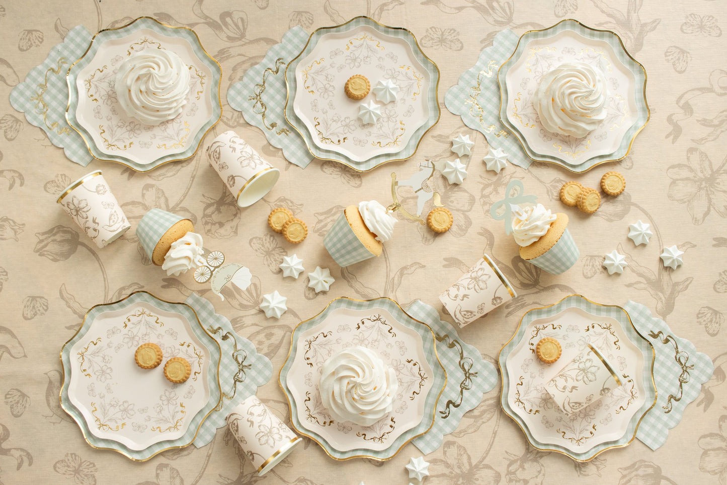 Decorative tableware with floral designs and small round cookies on a beige patterned background