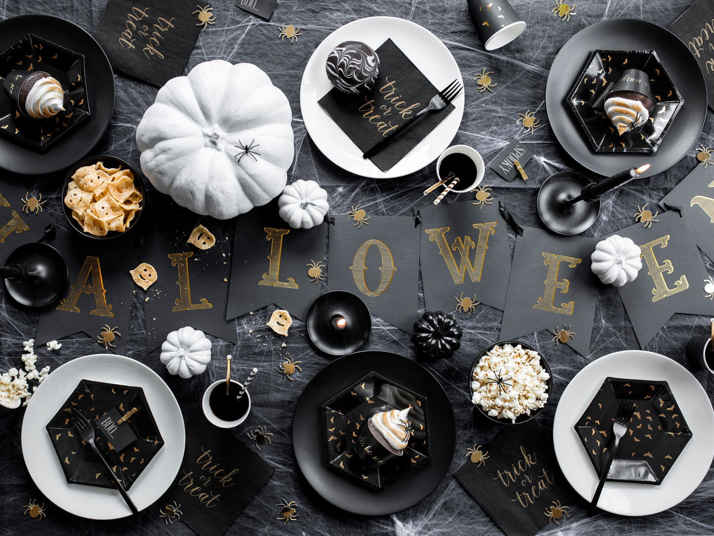 Halloween-themed table setting with black and gold decorations on a dark surface.