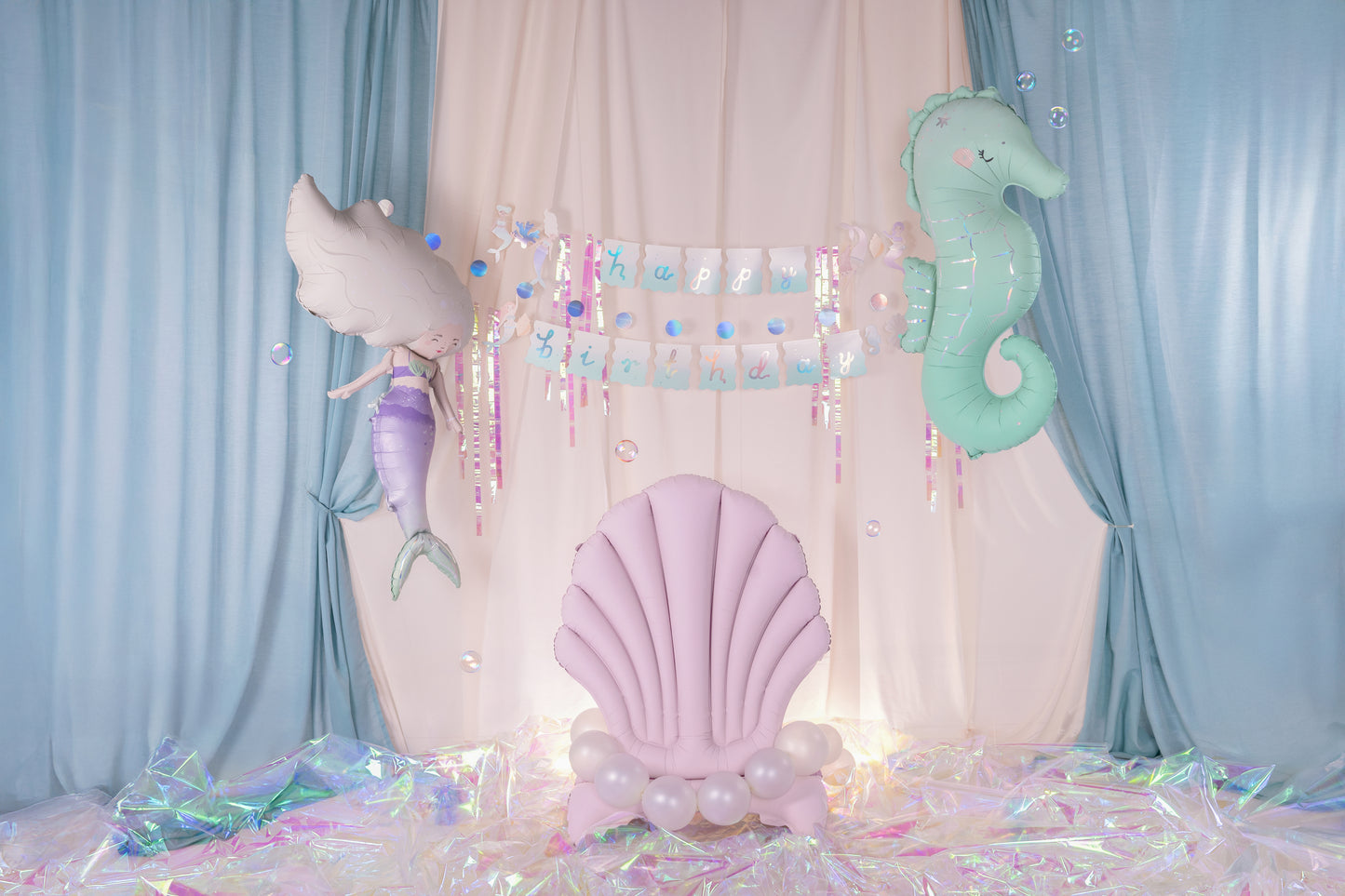 Mermaid themed birthday party decoration with pastel mermaid and seahorse foil balloons, pink shell balloon with pearls, iridescent backdrop, and 'Happy Birthday' banner — perfect for under the sea celebrations.