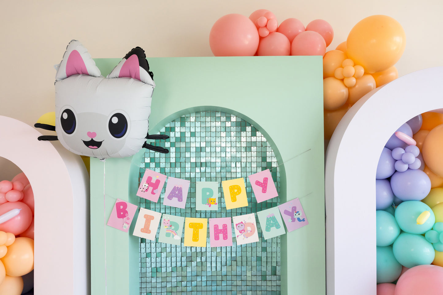 Pastel-colored birthday decorations with a plush cat toy and 'Happy Birthday' banner.