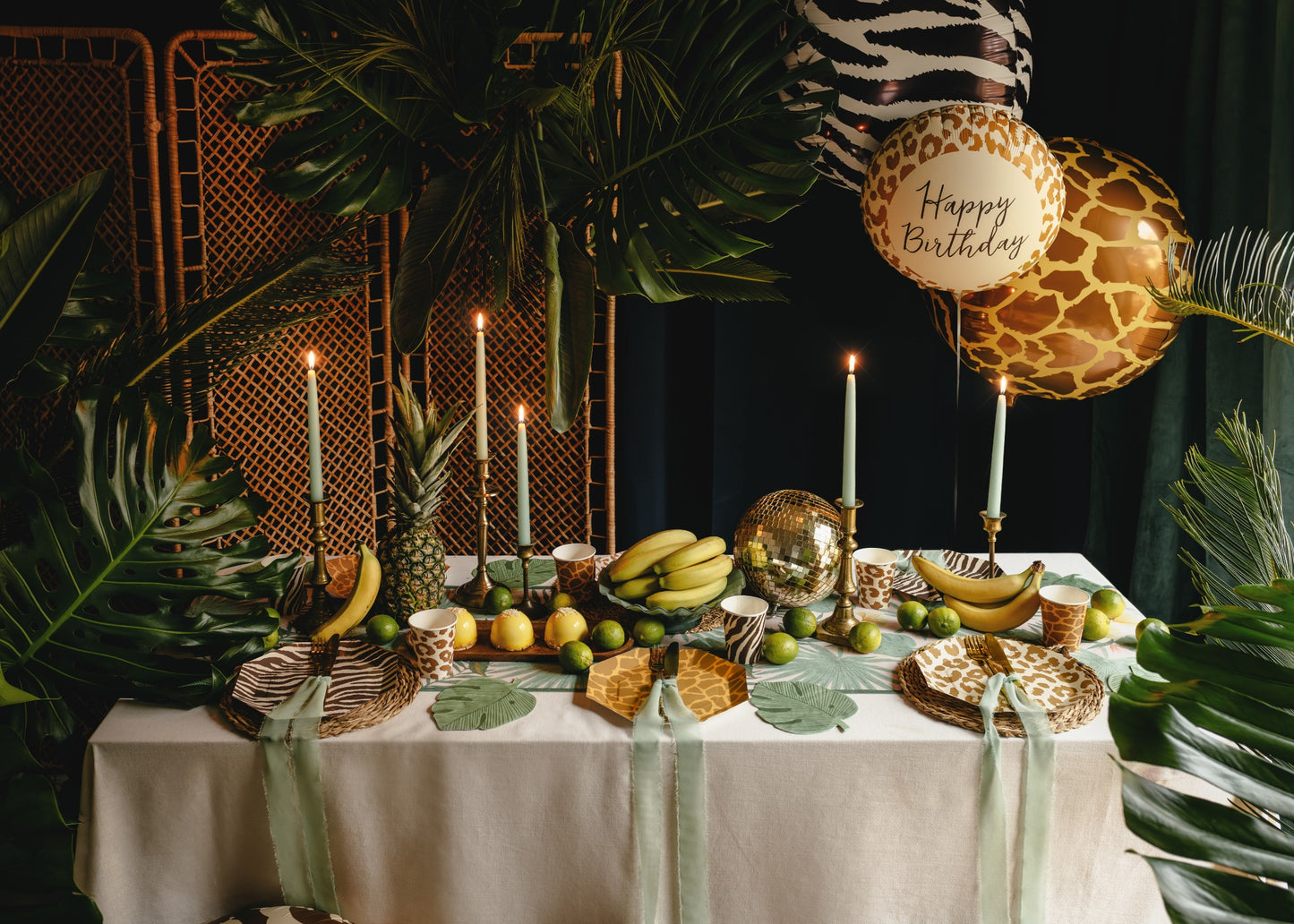 Decorated birthday table with balloons, candles, and fruits against a dark background