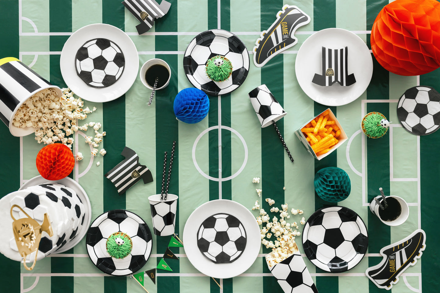 Decorative items including soccer-themed plates, balls, and shoes on a green and white striped background.