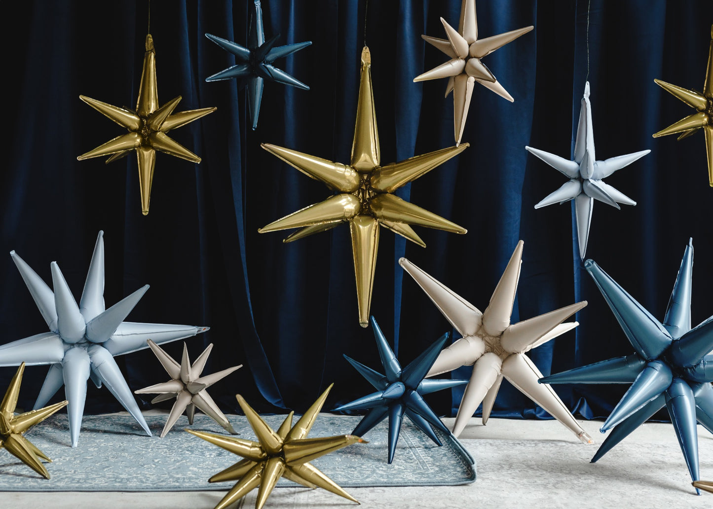 Assorted 3D star foil balloons in gold, silver, and blue tones, hanging and arranged for space-themed party or holiday decorations.