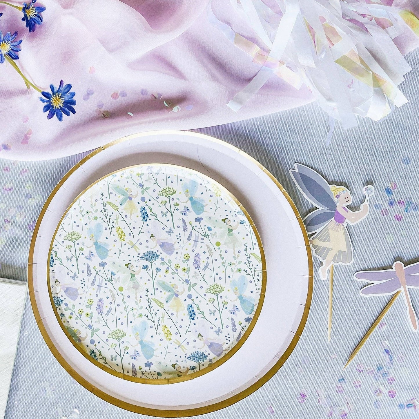 Round paper plate with floral design on a light gray background with fairy decorations.