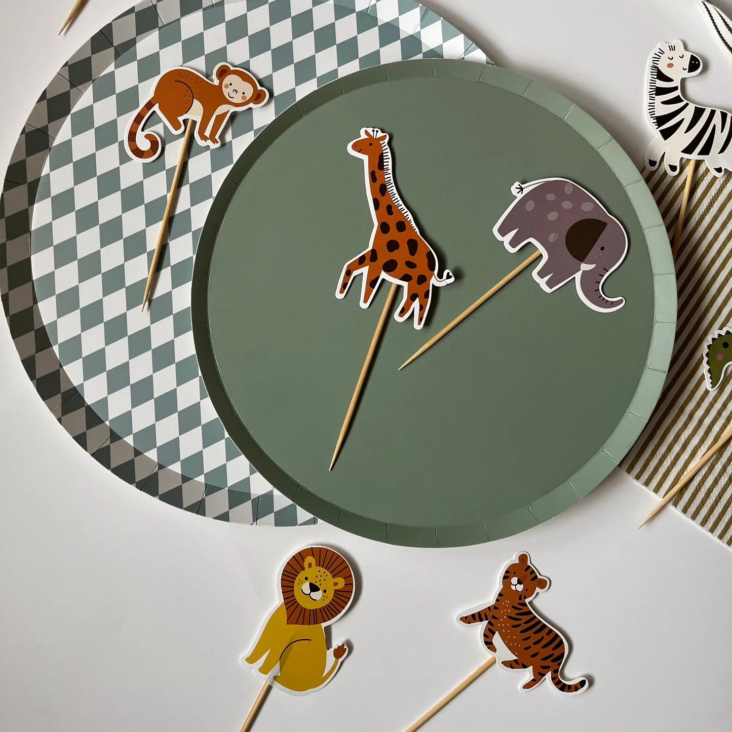 Animal-themed paper cupcake toppers with a green plate and checkered plate.