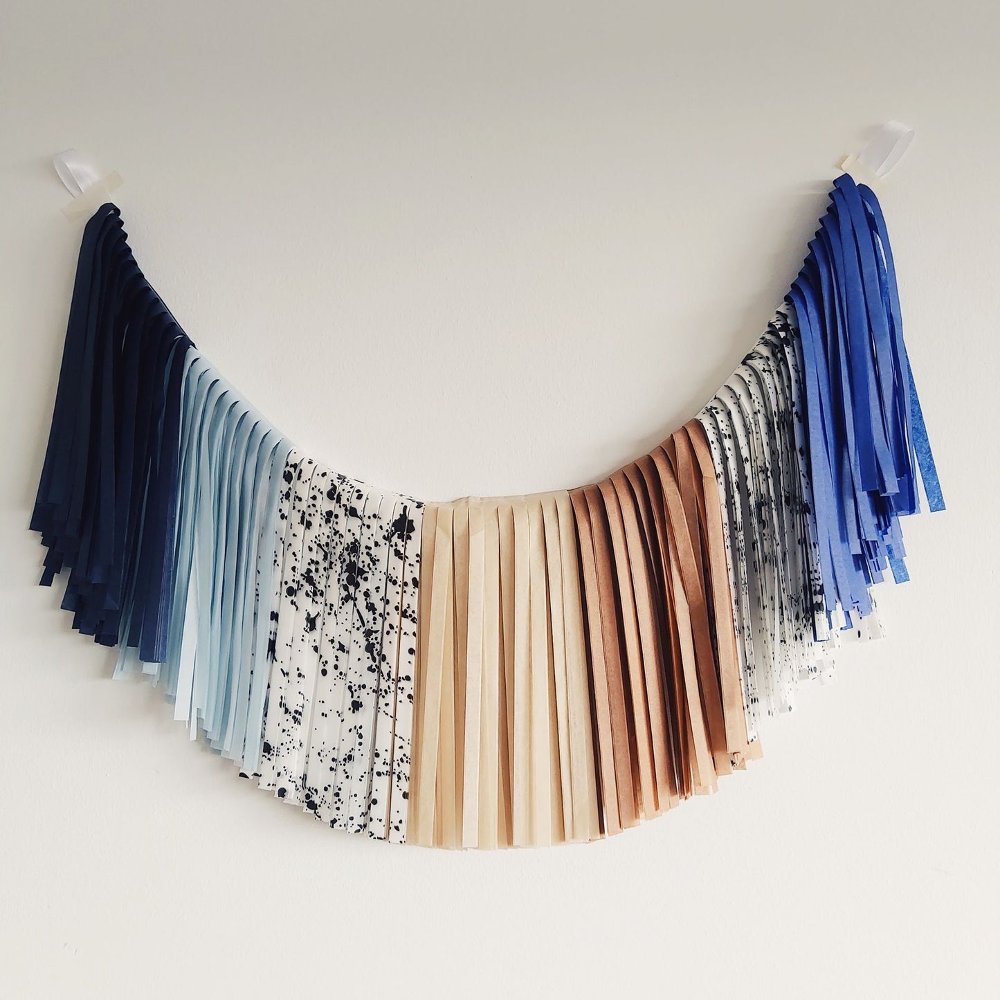 Colorful tassel garland hanging against a white wall