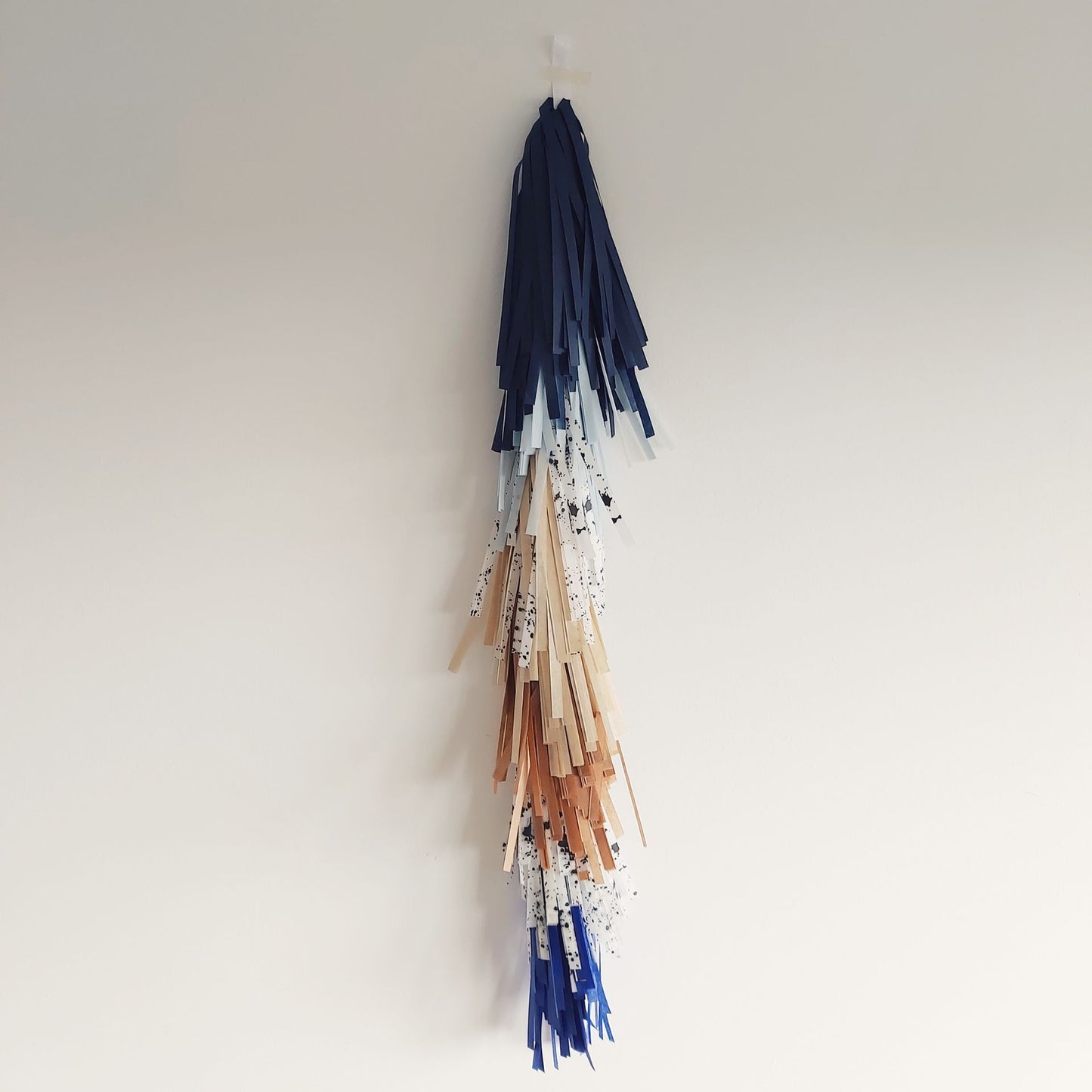 Decorative wall hanging with colorful tassels on a plain background
