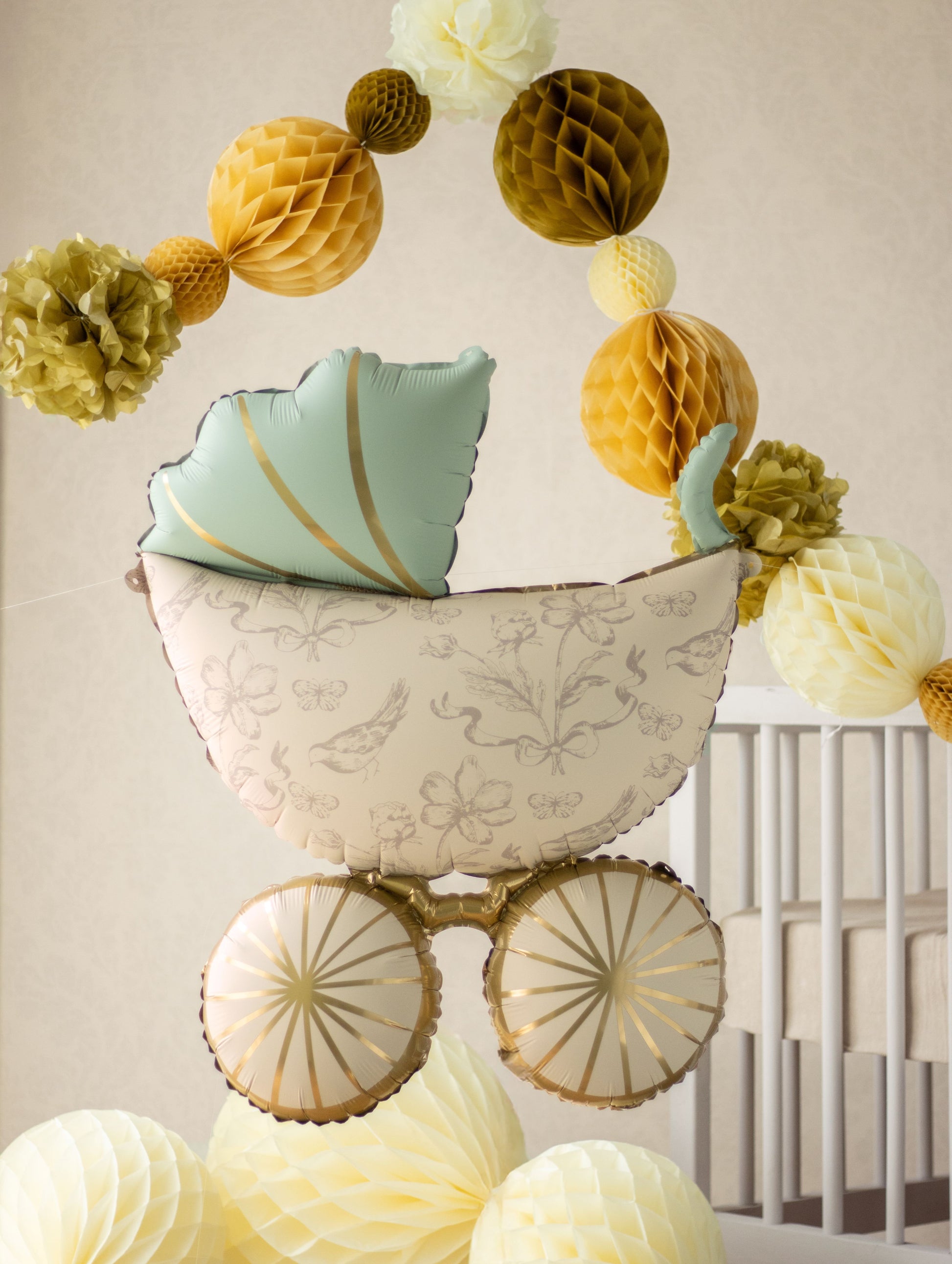 Decorative baby shower crib with hanging paper flowers against a neutral background