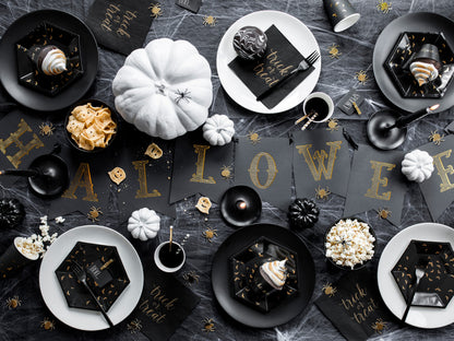 Halloween-themed table setting with black and gold decorations, pumpkins, and treats.