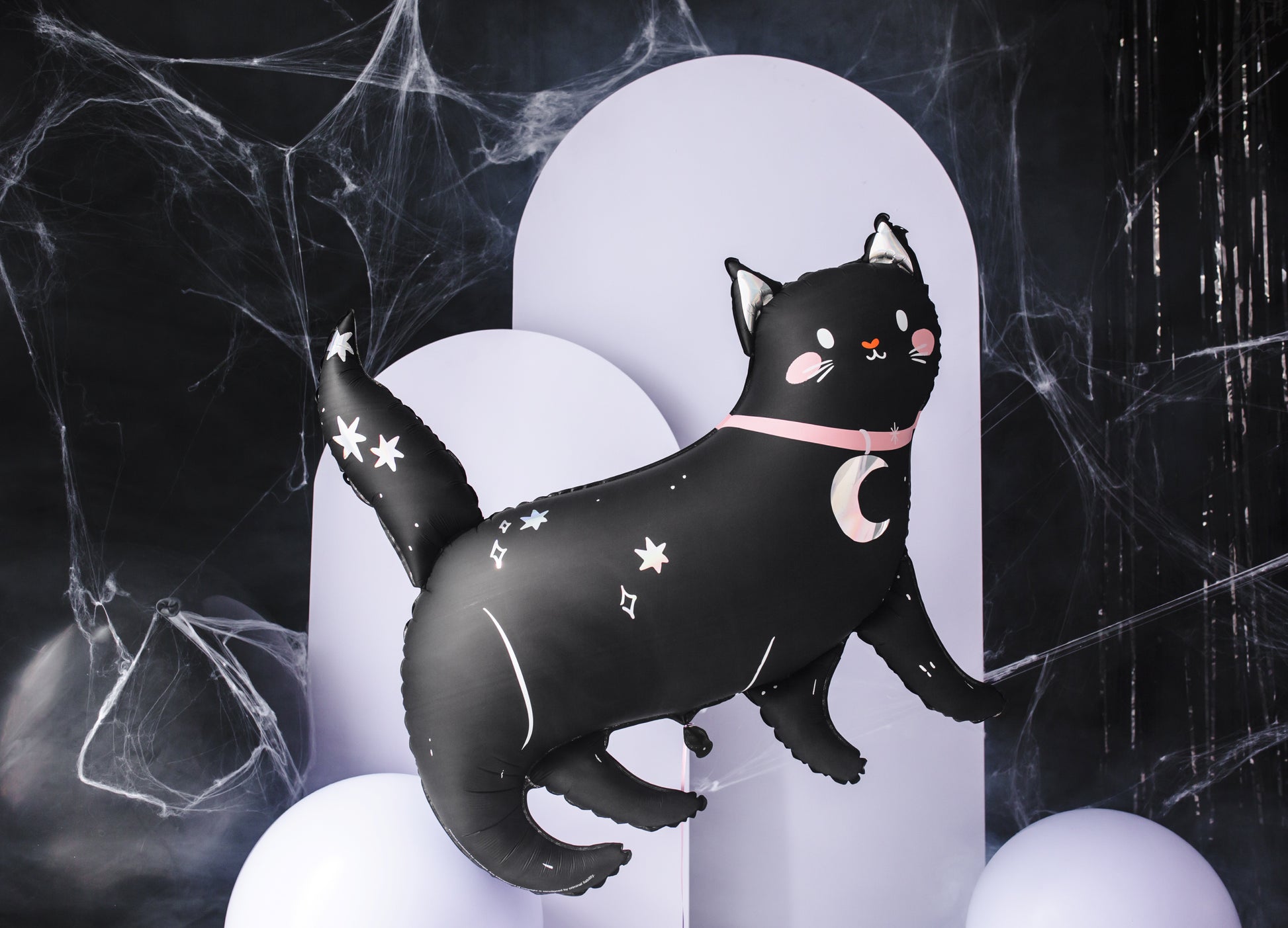 Black cat foil balloon with star and moon designs on a dark background