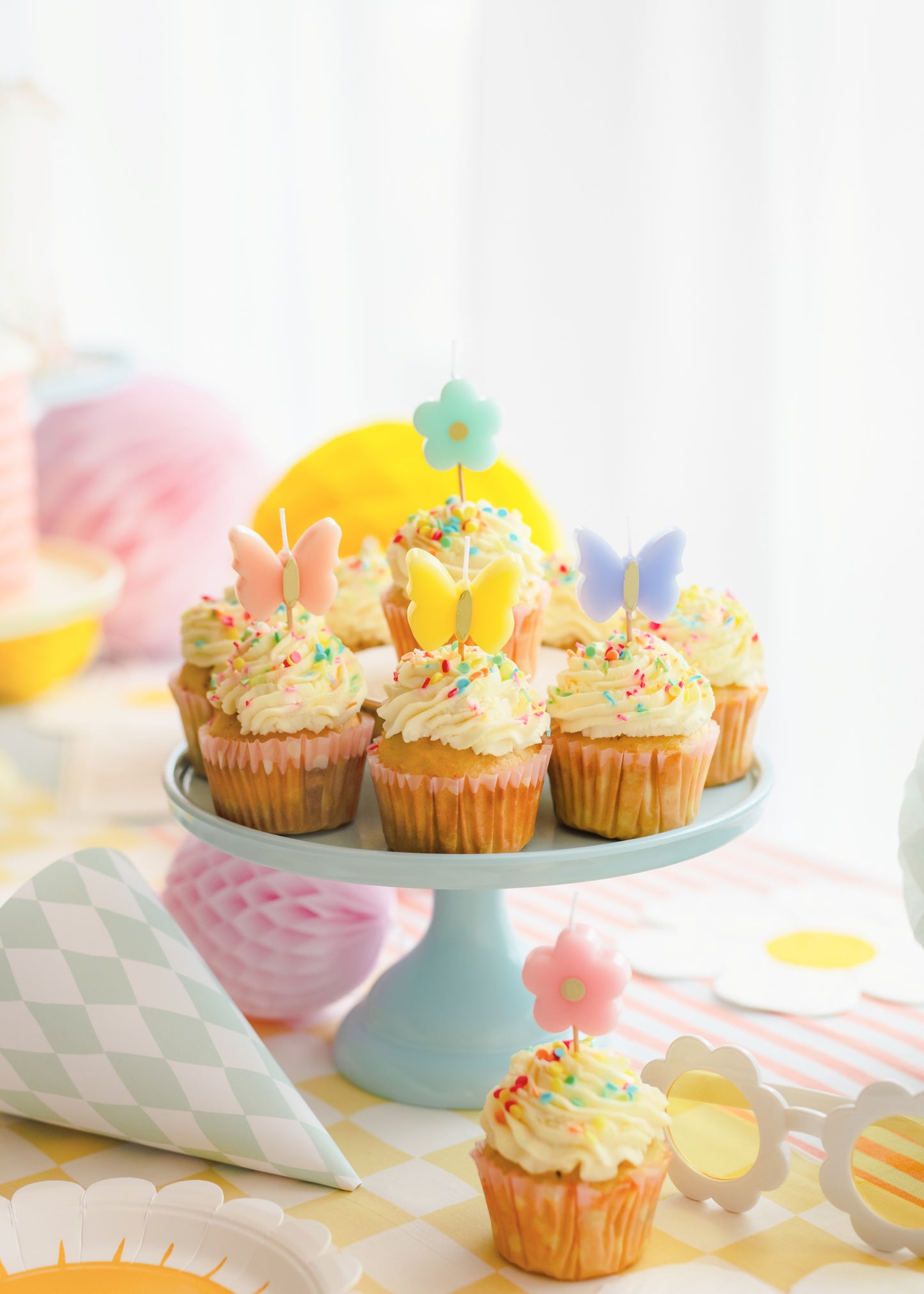 Decorative cupcakes on a cake stand with colorful decorations on a light background