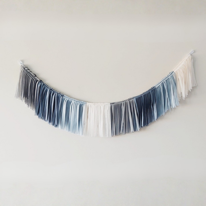 Fringe banner with blue and white tassels on a plain background