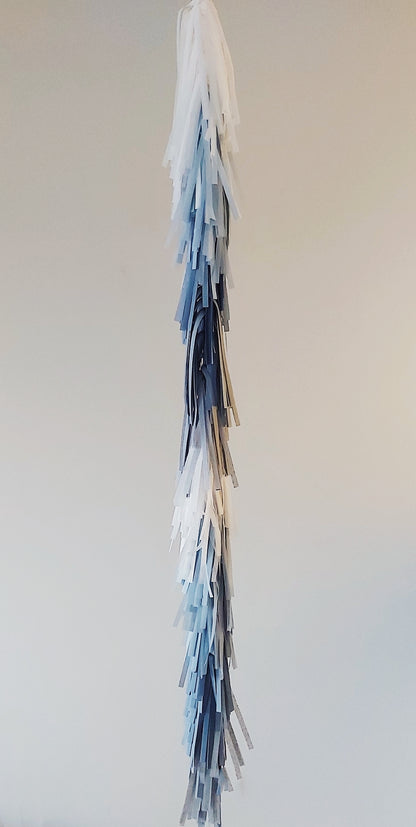 Decorative tassel with blue and white strands on a plain background