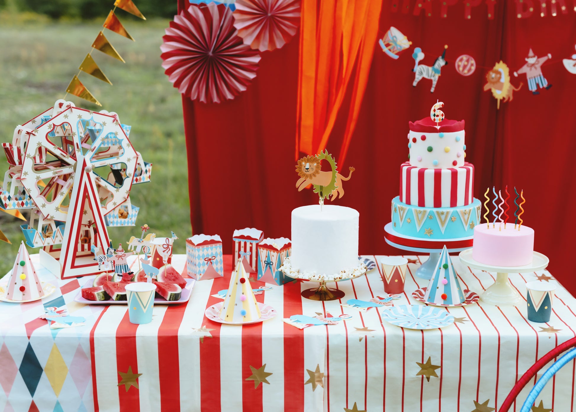 Carnival-themed birthday party setup with cake, decorations, and tableware.