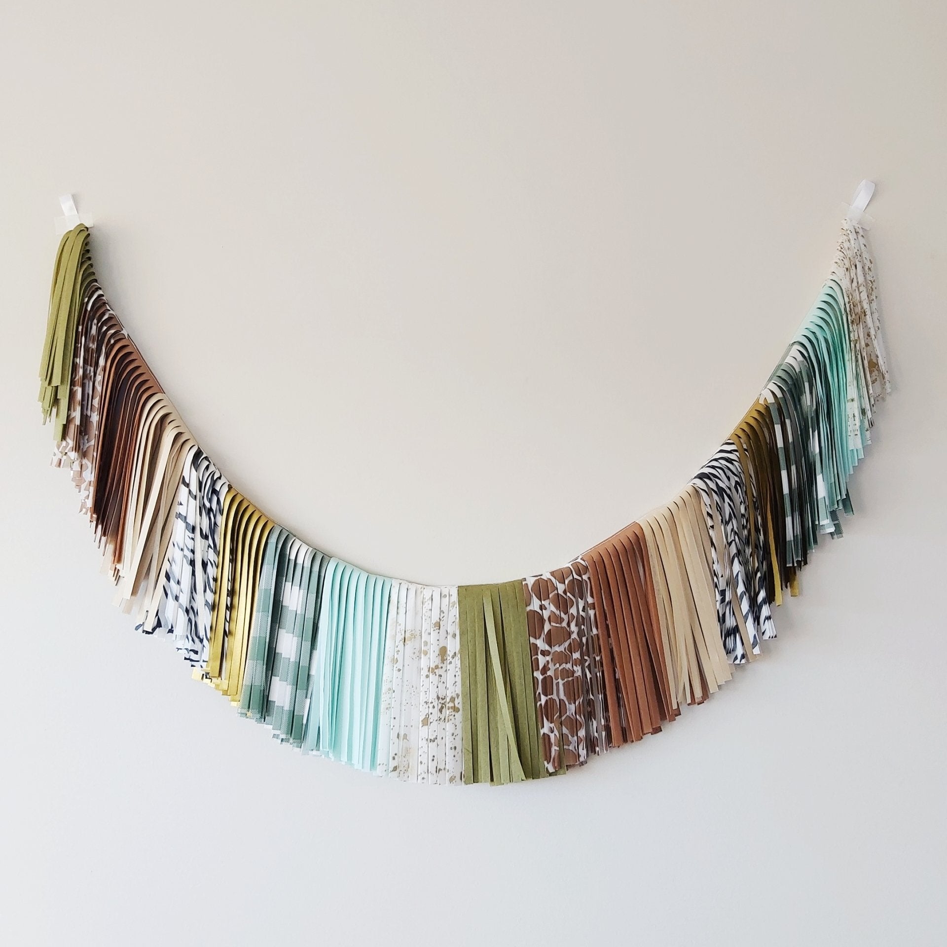 Decorative wall hanging made of patterned fabric strips on a plain background