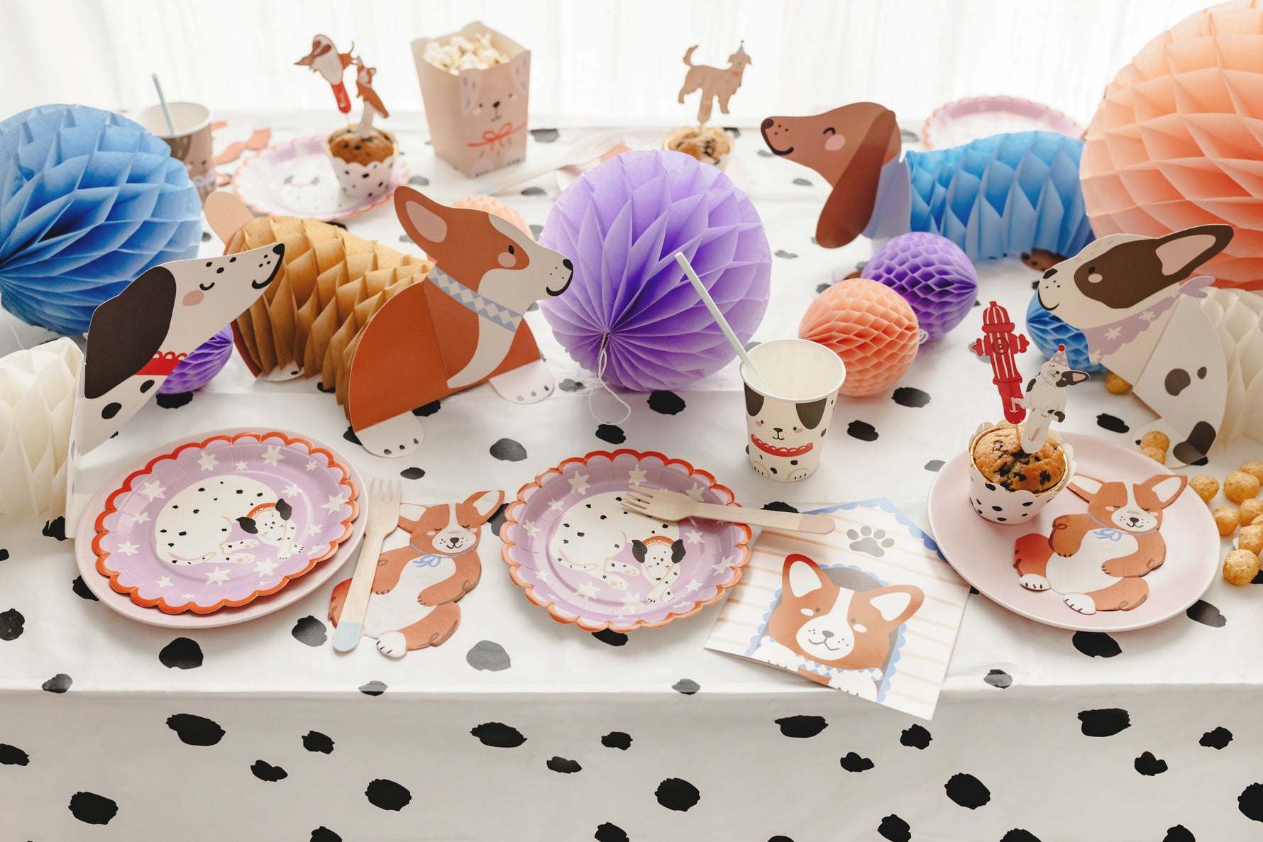 Children's party table with animal-themed decorations and plates on a polka dot tablecloth.