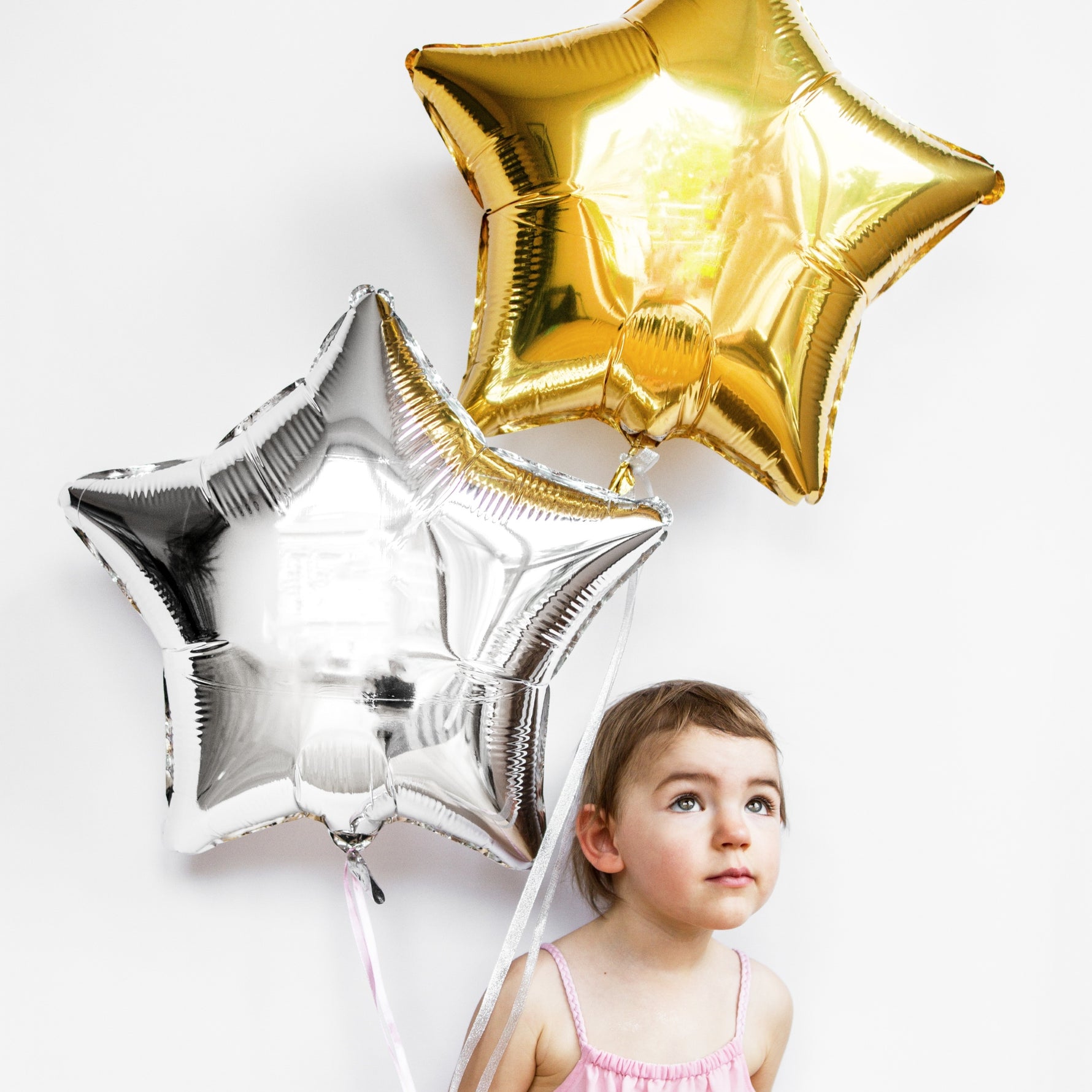 Child holding gold and silver star-shaped balloons.