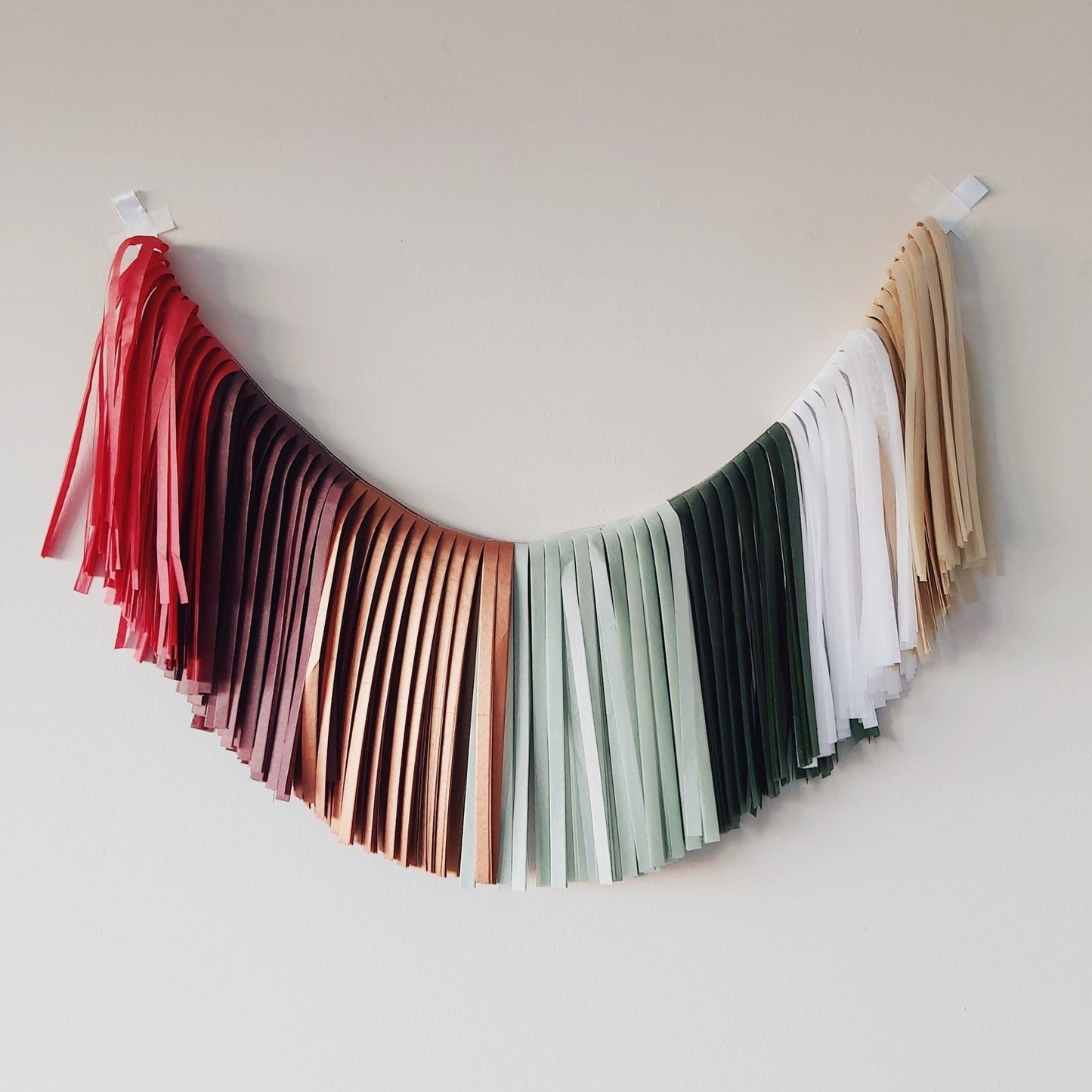 Colorful tassel garland hanging against a plain wall