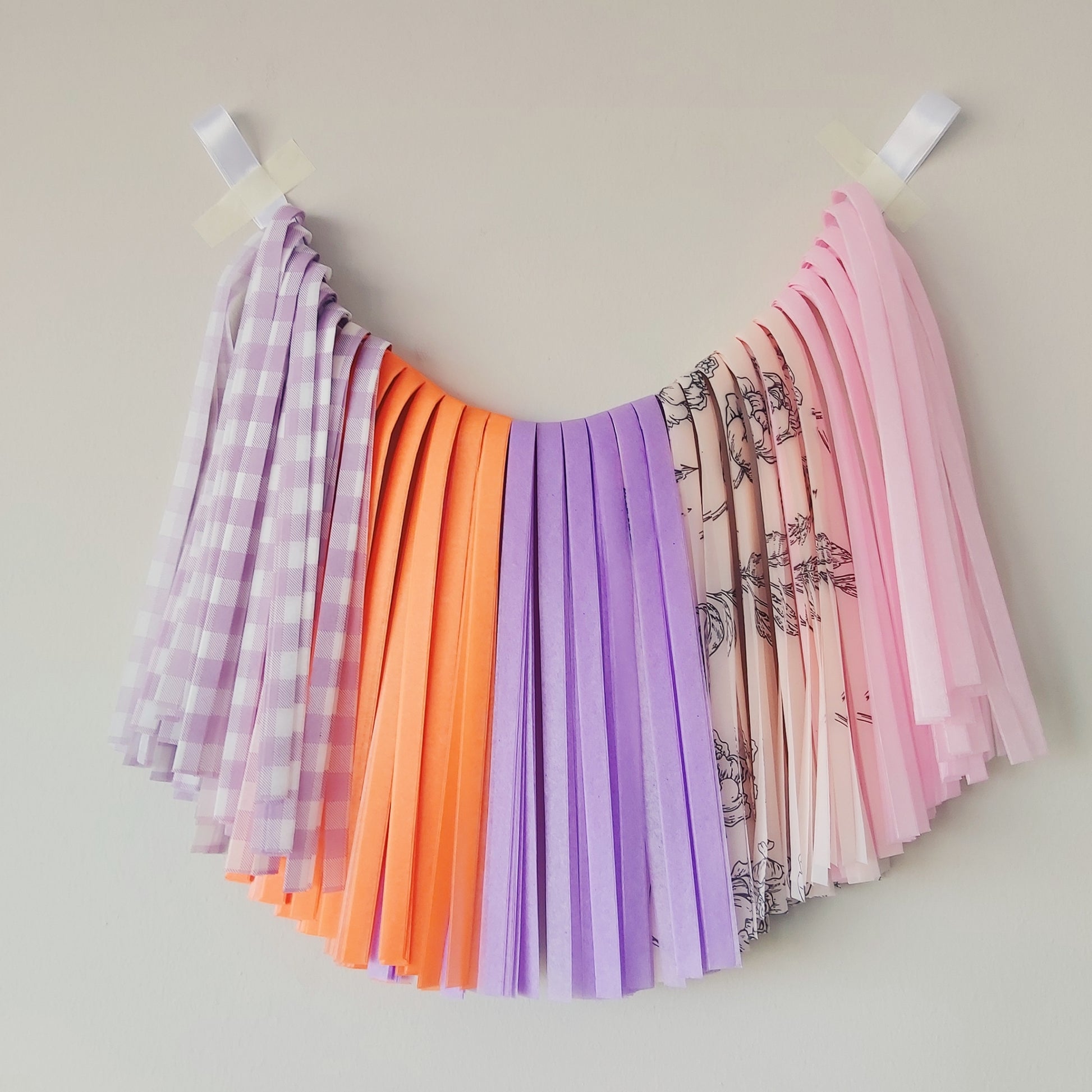 Colorful fabric strips hanging on a line against a plain background