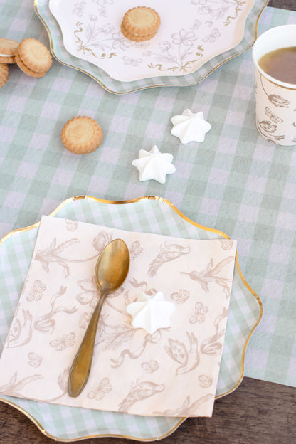 Tea set with cookies, star-shaped cookies, and a spoon on a checkered tablecloth.