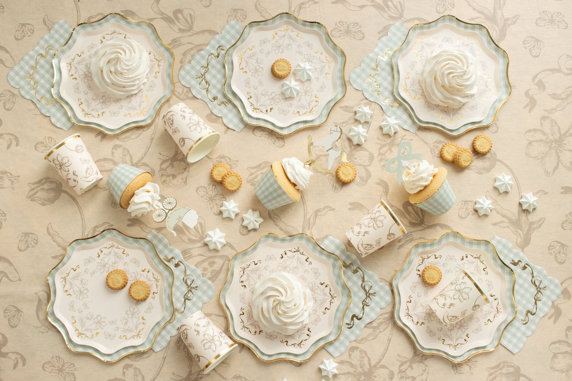 Decorative tableware with floral designs and small round cookies on a beige patterned background