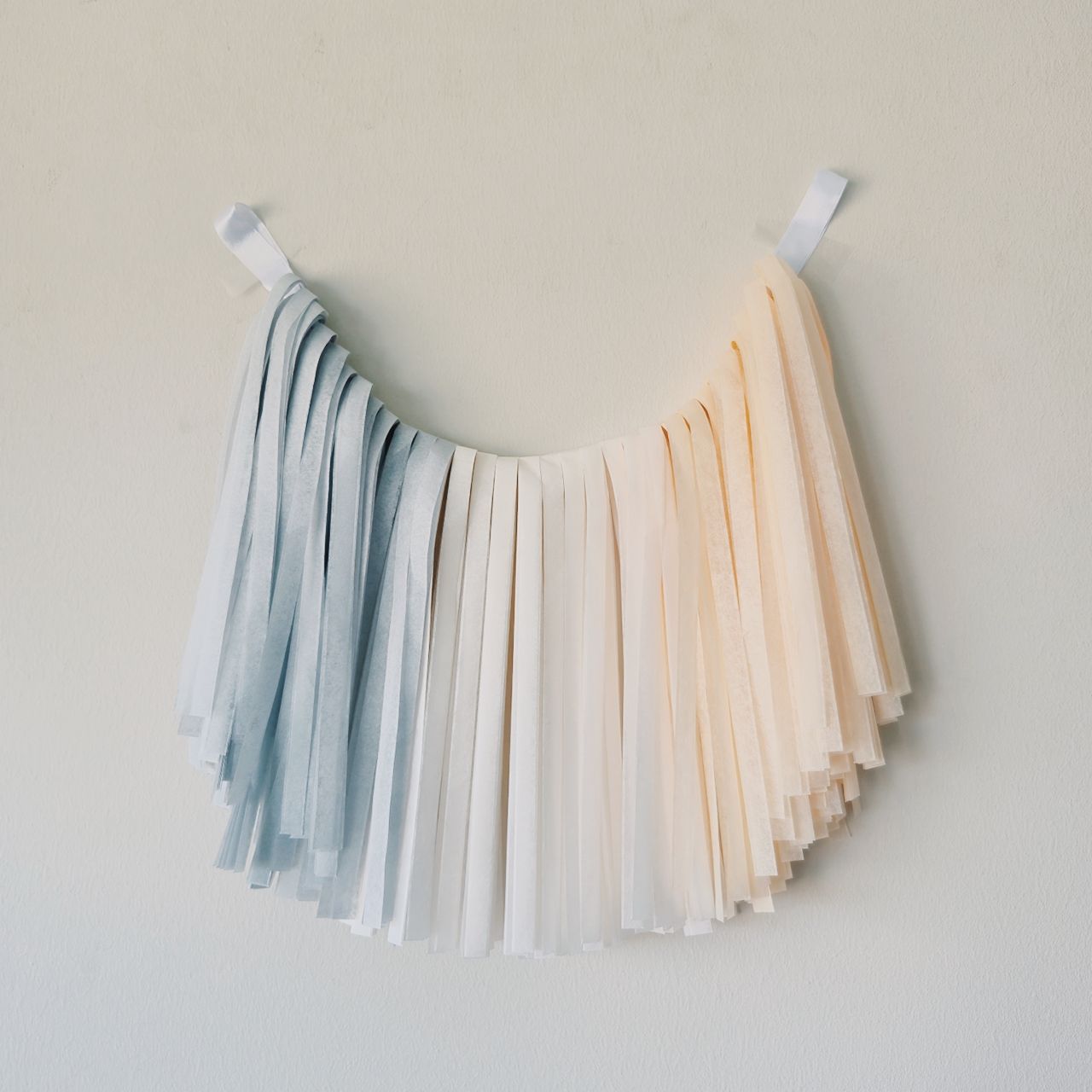 Tissue paper tassel garland in pastel colors on a neutral background