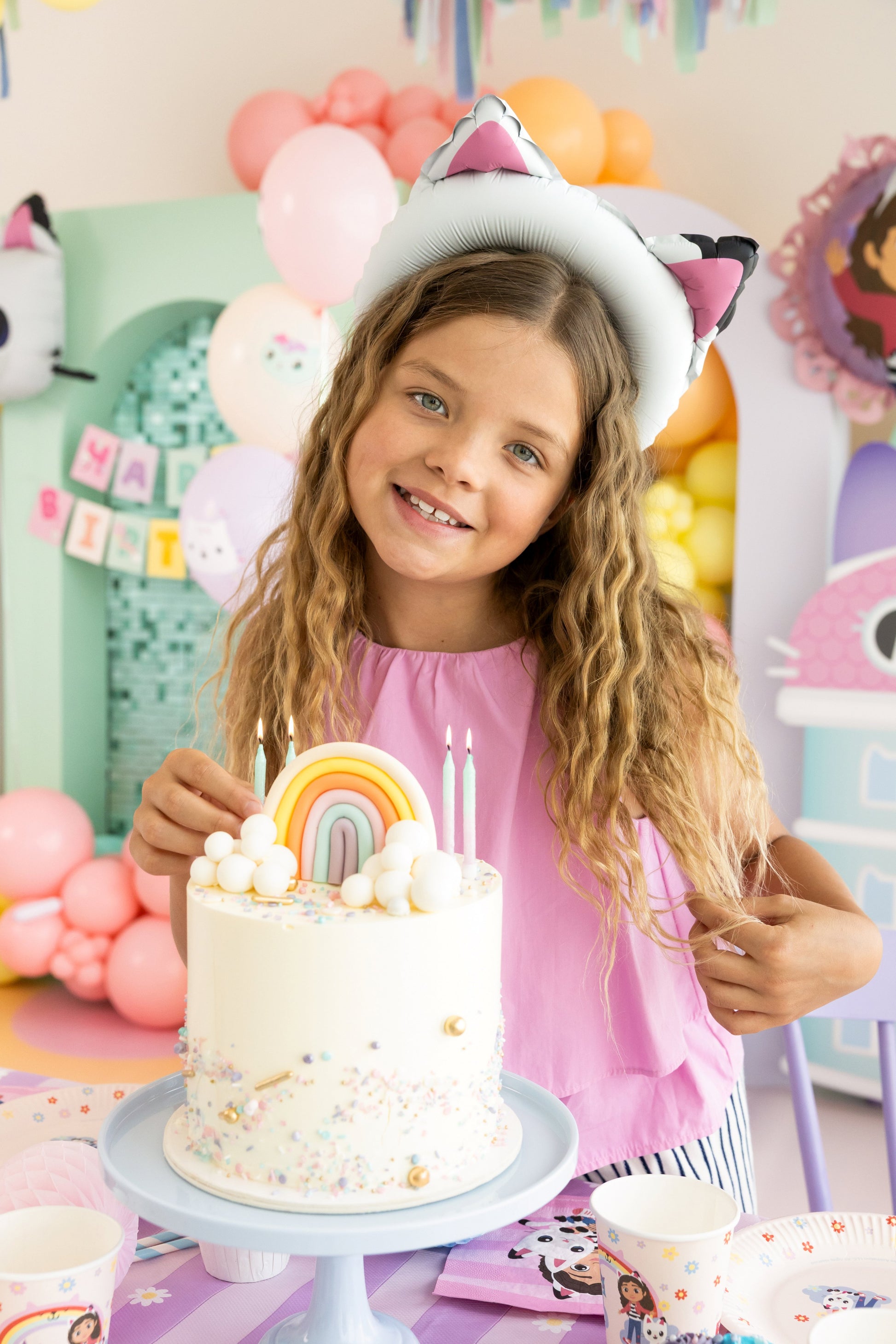 Young girl with a birthday cake and colorful decorations at a party.