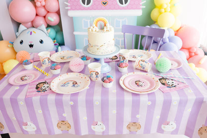 Children's birthday party setup with a cake, plates, and balloons on a table.