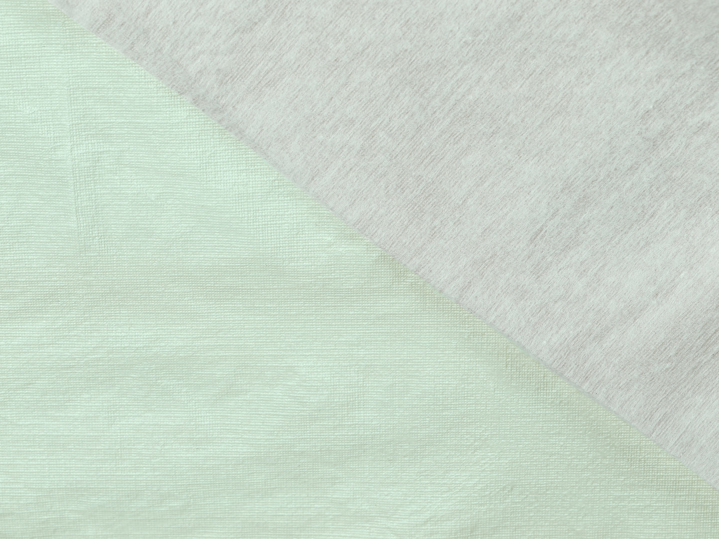 Close-up of a fabric with a diagonal pattern transitioning from light green to white.