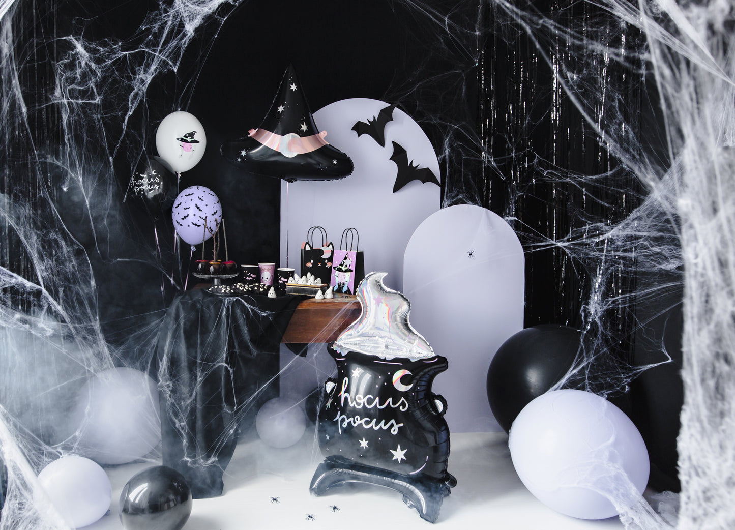 Halloween-themed decor with balloons, a black cat sign, and spider webs.