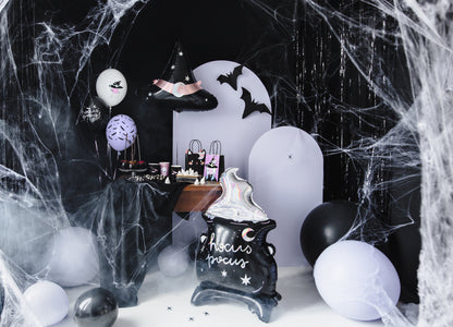 Halloween-themed decor with balloons, a black cat sign, and spider webs.