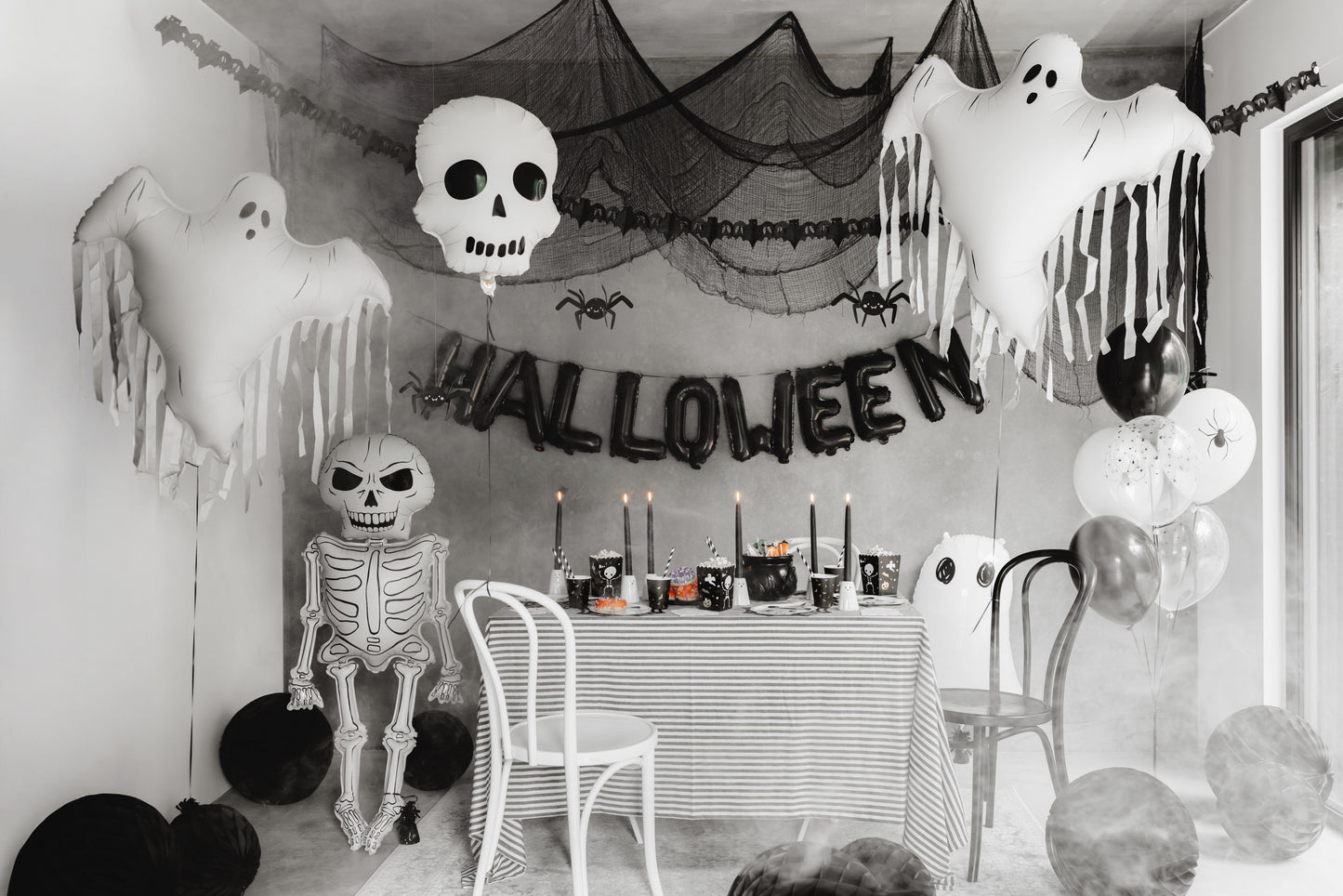 Halloween-themed room with decorations including ghosts, a skeleton, and balloons.