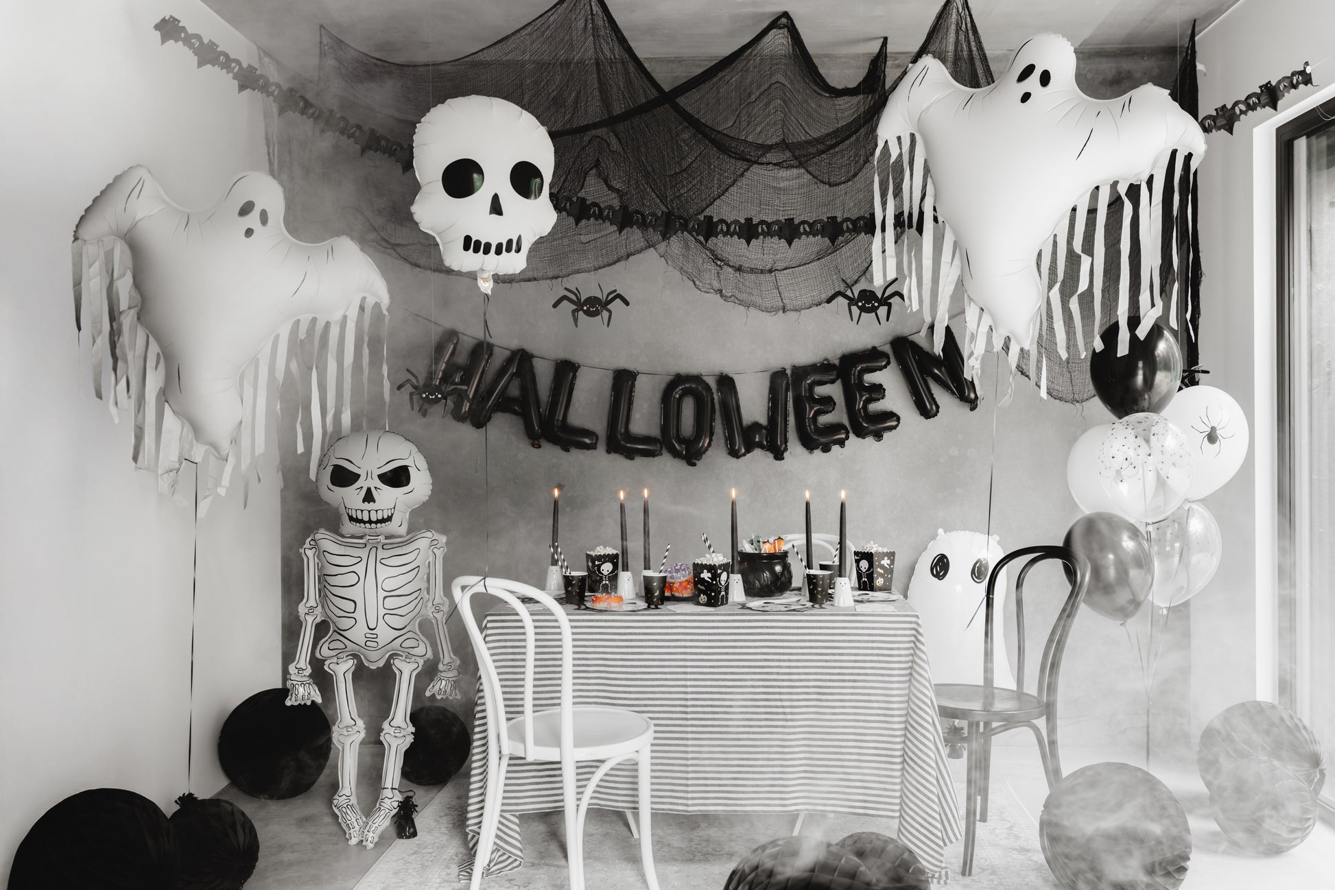 Halloween-themed room with decorations including ghosts, a skeleton, and balloons.
