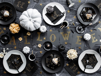 Halloween-themed table setting with black and gold decorations on a dark surface.