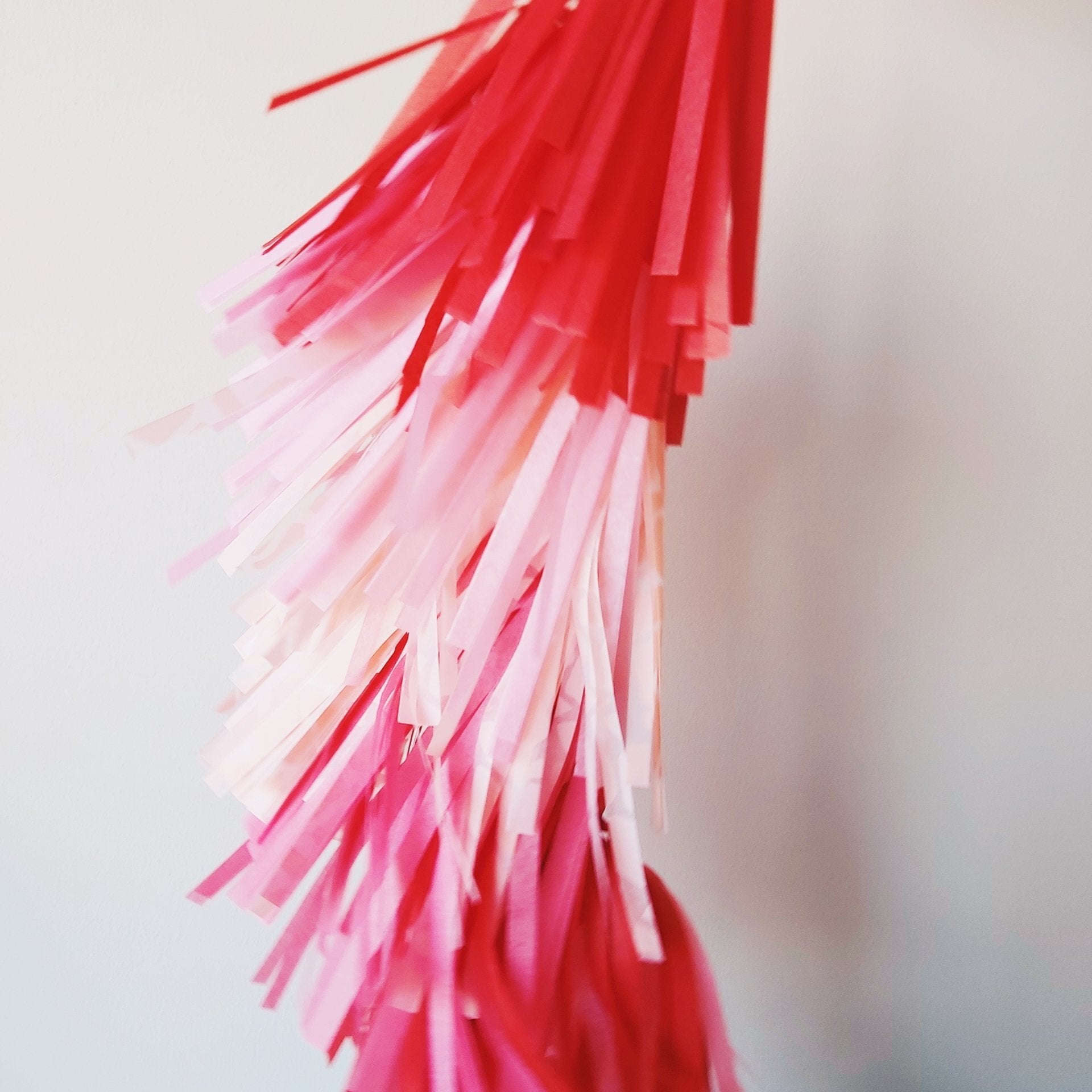 Close-up of red and pink tinsel strands against a blurred background