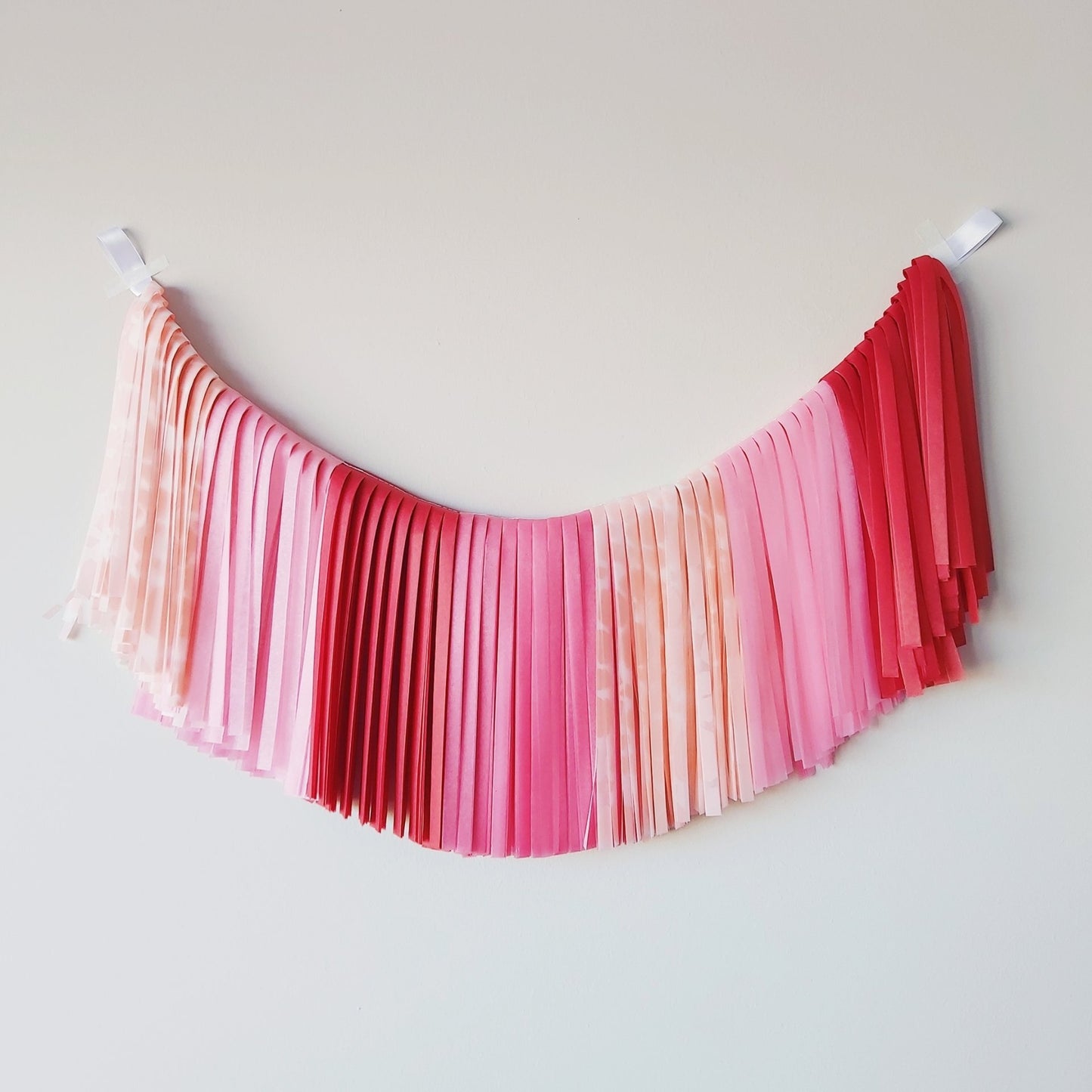 Pink and red gradient fabric hanging on a white wall