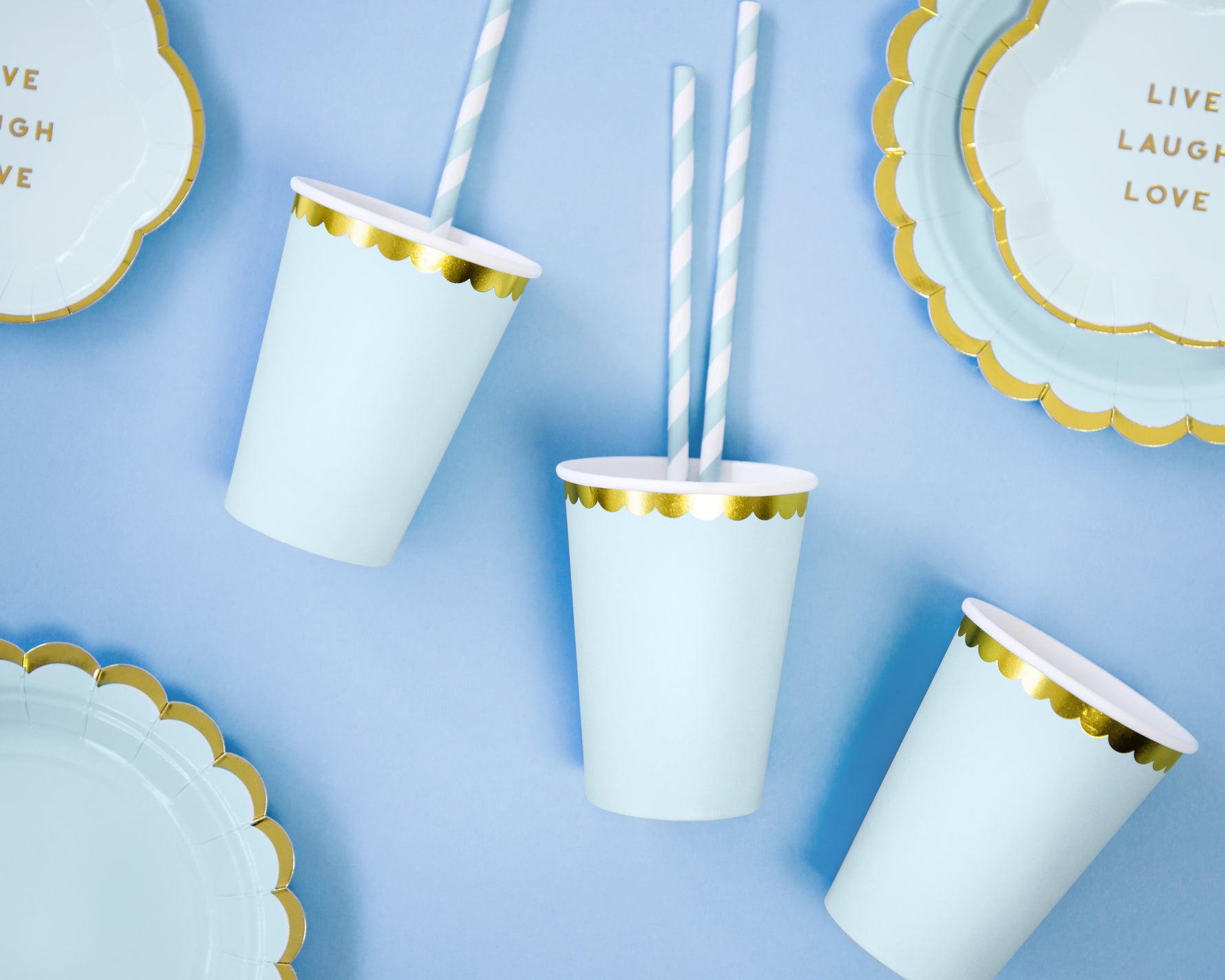 Light blue paper cups and plates with gold trim and striped straws