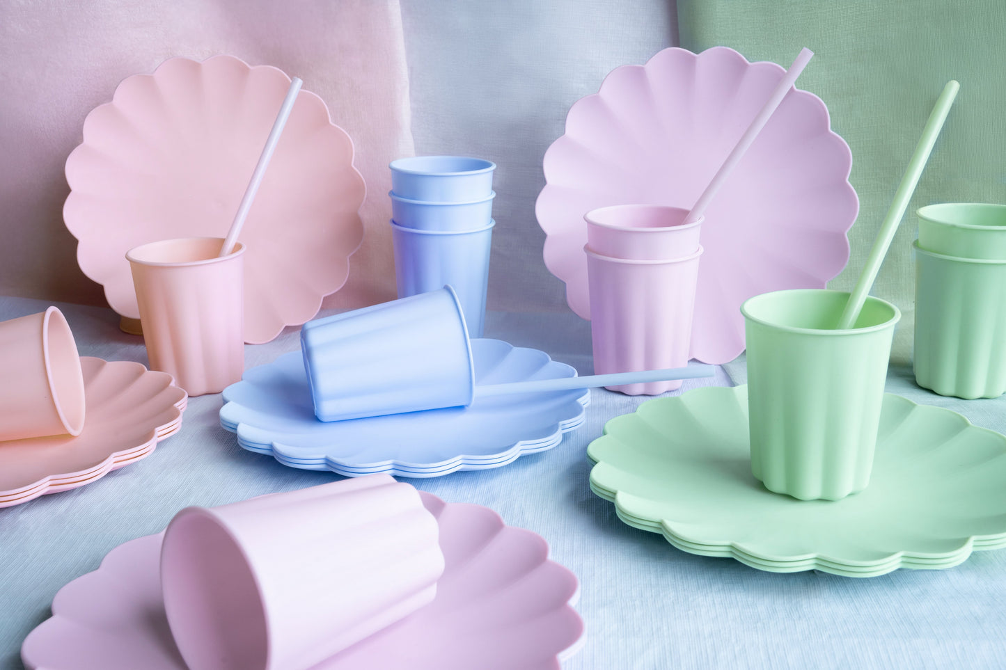 Colorful paper plates and cups with straws on a light blue surface
