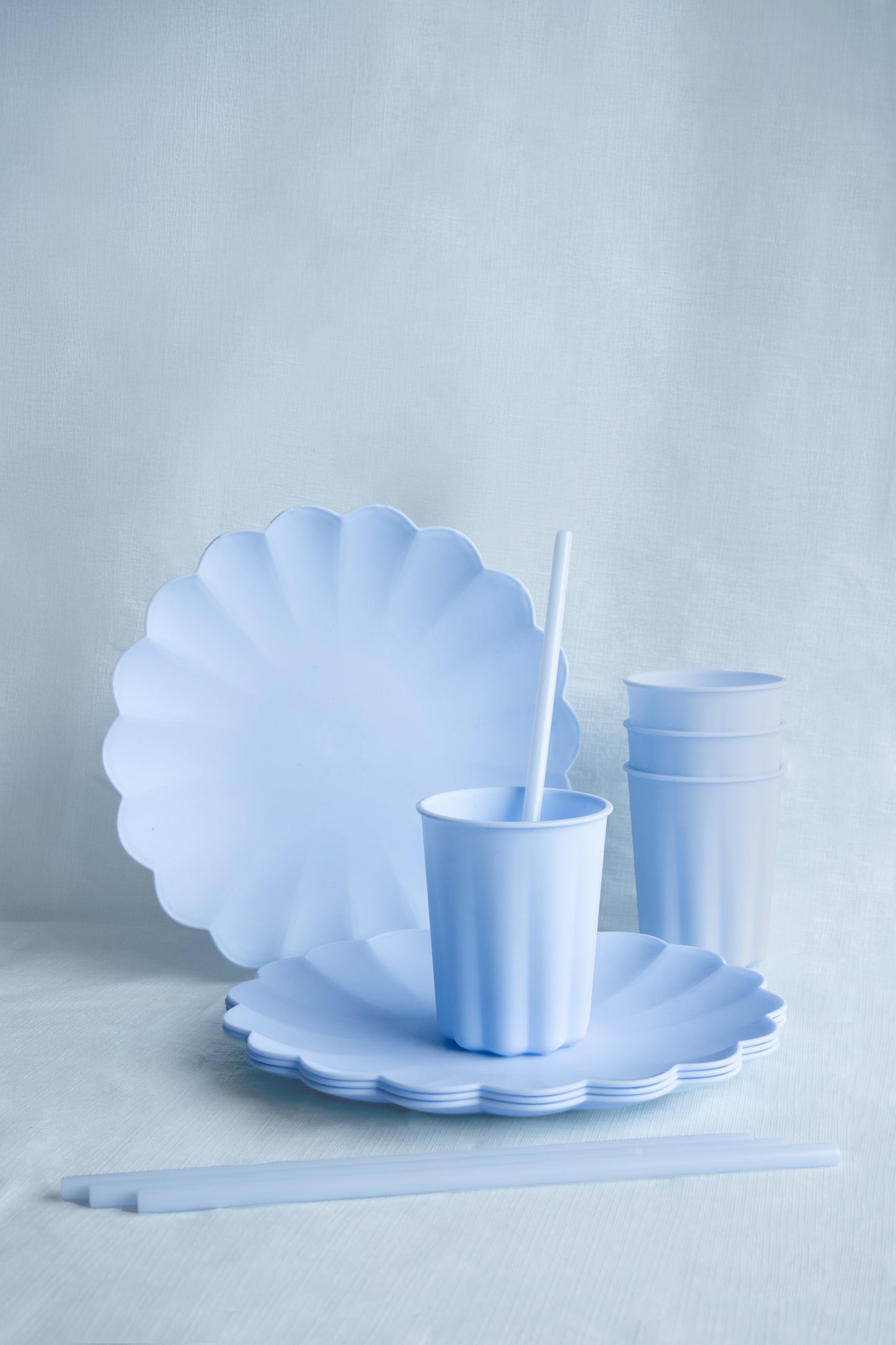 Light blue scalloped plates and cups on a light gray background