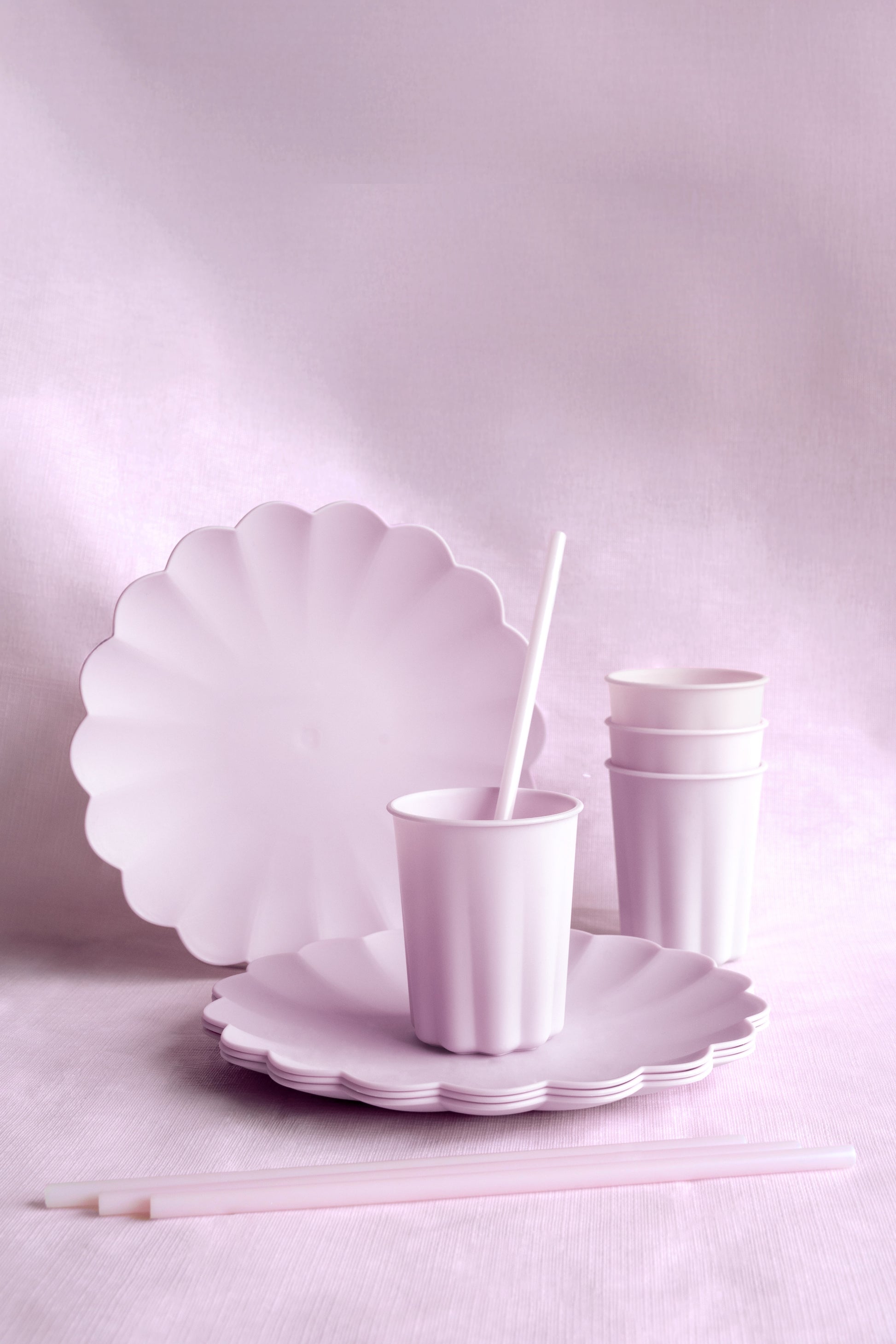 Purple scalloped plates and cups on a light pink background