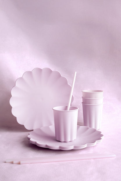 Purple scalloped plates and cups on a light pink background