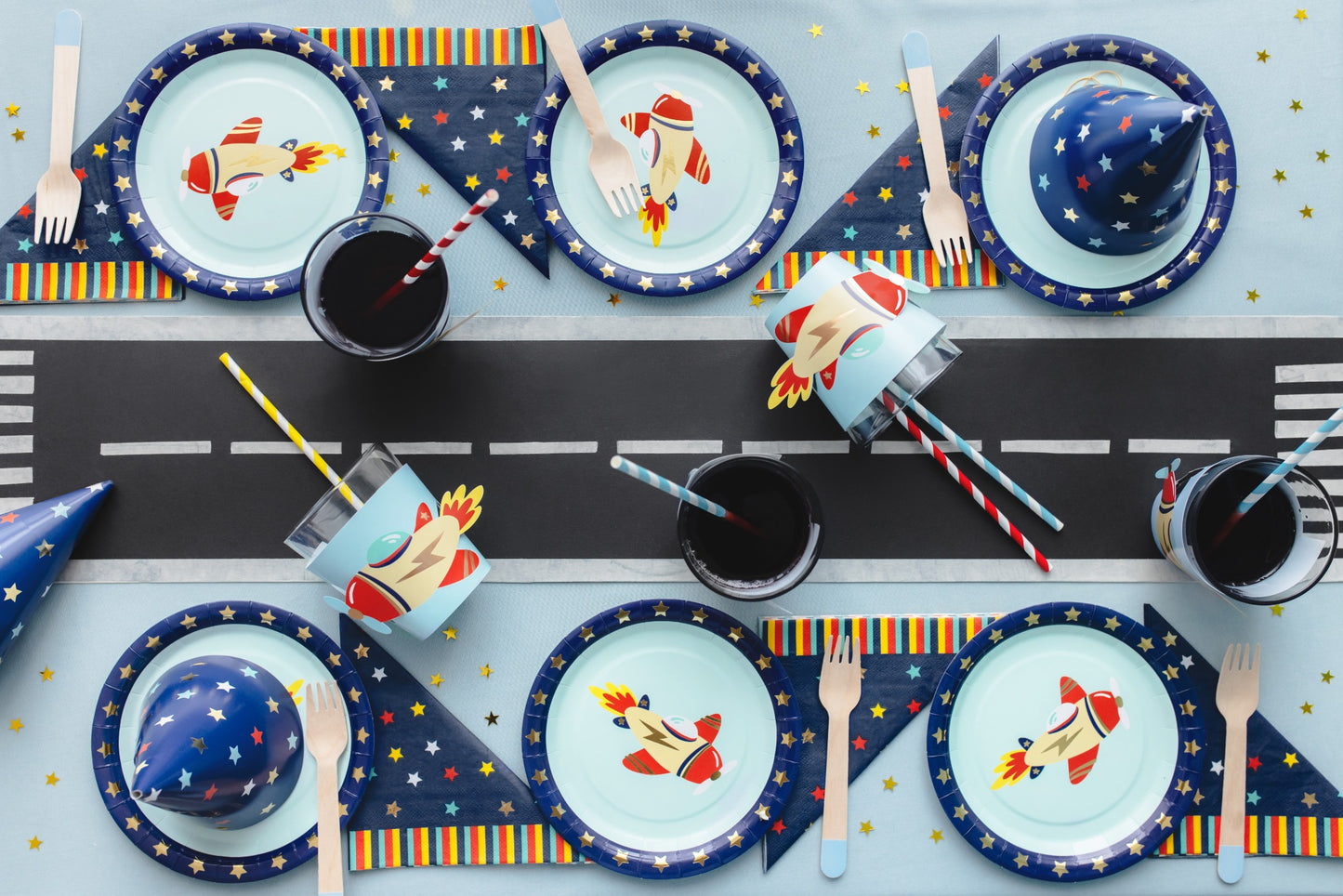 Birthday party table with a rocket runway centerpiece, rocket cups, plates, napkins, and party hats in space theme