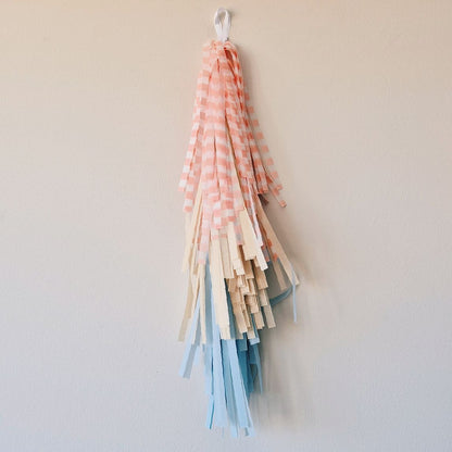 Decorative hanging with striped ribbons in pink, beige, and blue on a plain background