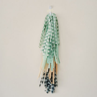Decorative tassel with plaid pattern hanging on a beige wall