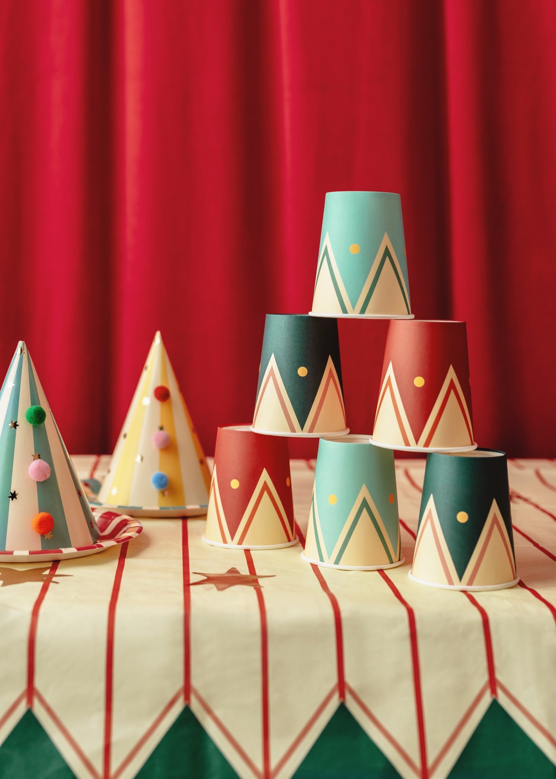 Colorful paper cups with vintage circus tent inspired designs in turquoise, red, and dark green with zigzag patterns