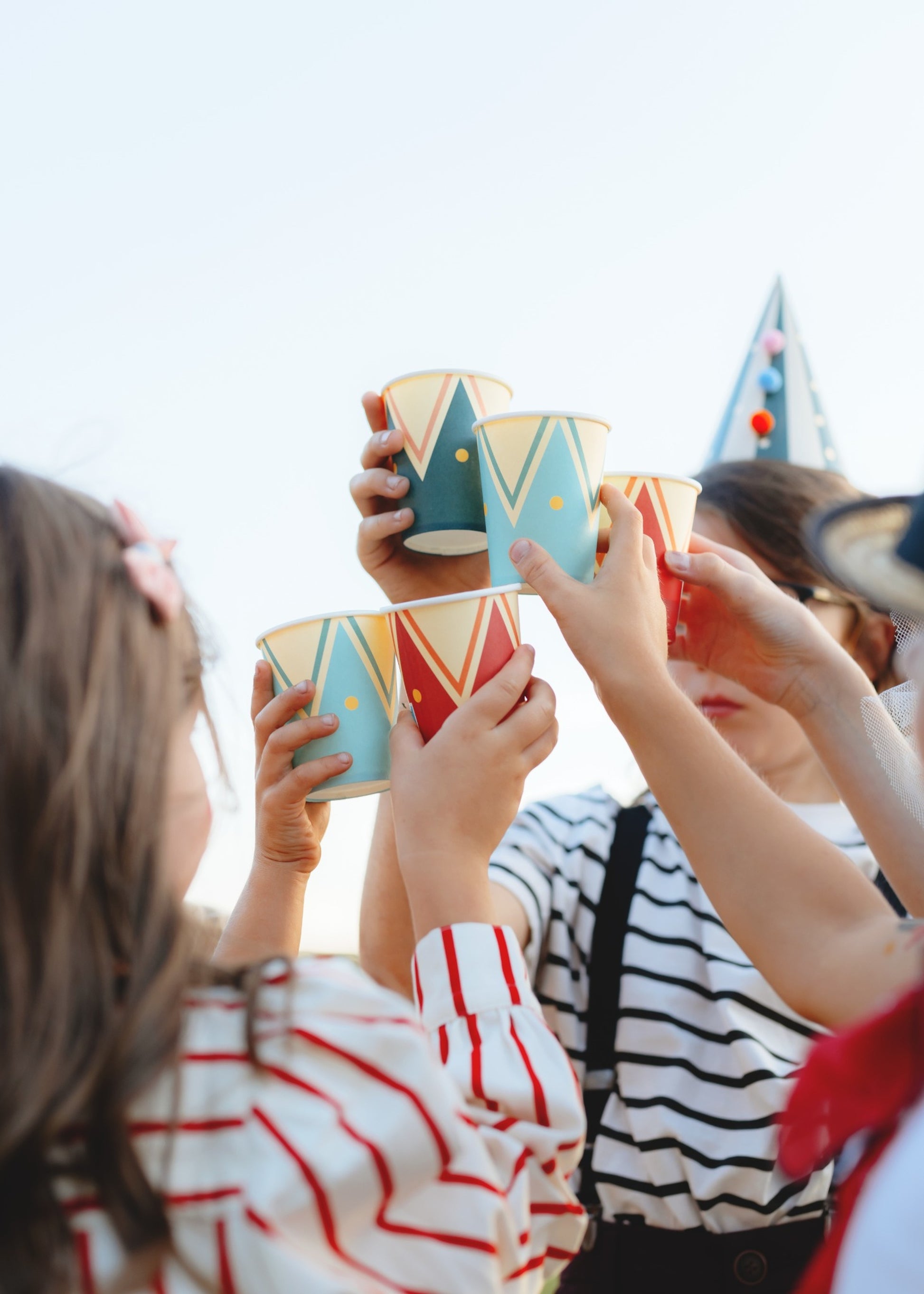 Colorful paper cups with vintage circus tent inspired designs in turquoise, red, and dark green with zigzag patterns