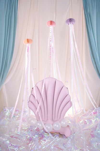 Pink shell balloon with fairy lights against a draped curtain backdrop