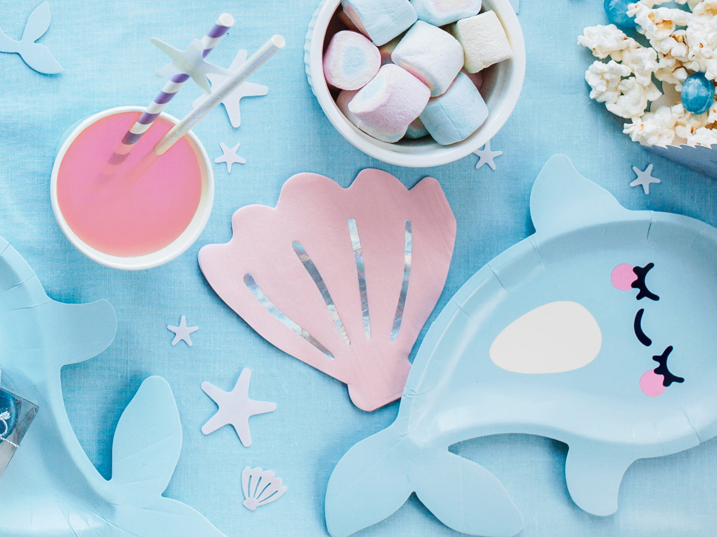 Pink paper napkins shaped like seashells with holographic accents — perfect for mermaid birthday party table settings.