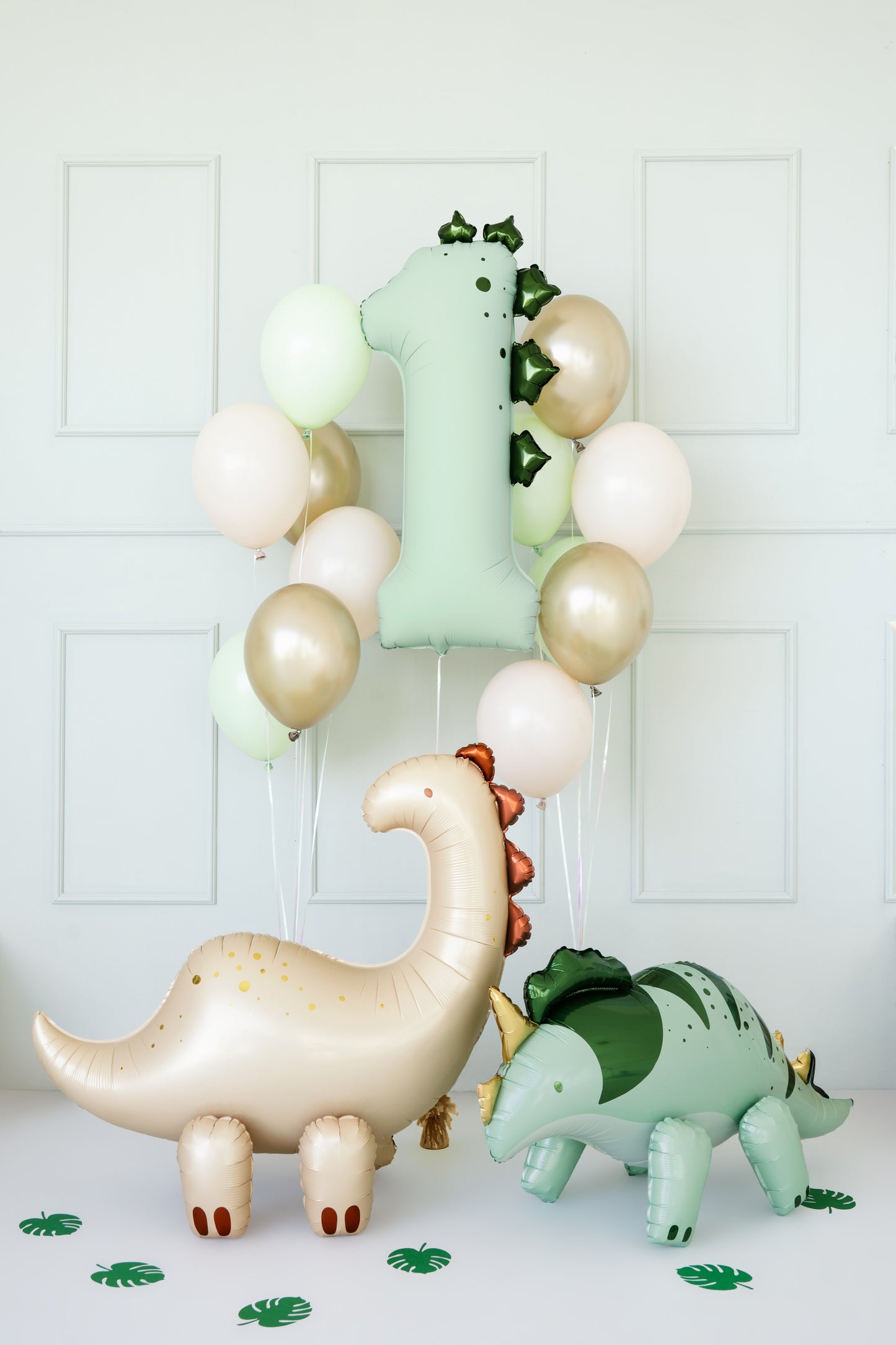 Decorative balloons shaped like a dinosaur, number, and leaves on a white background