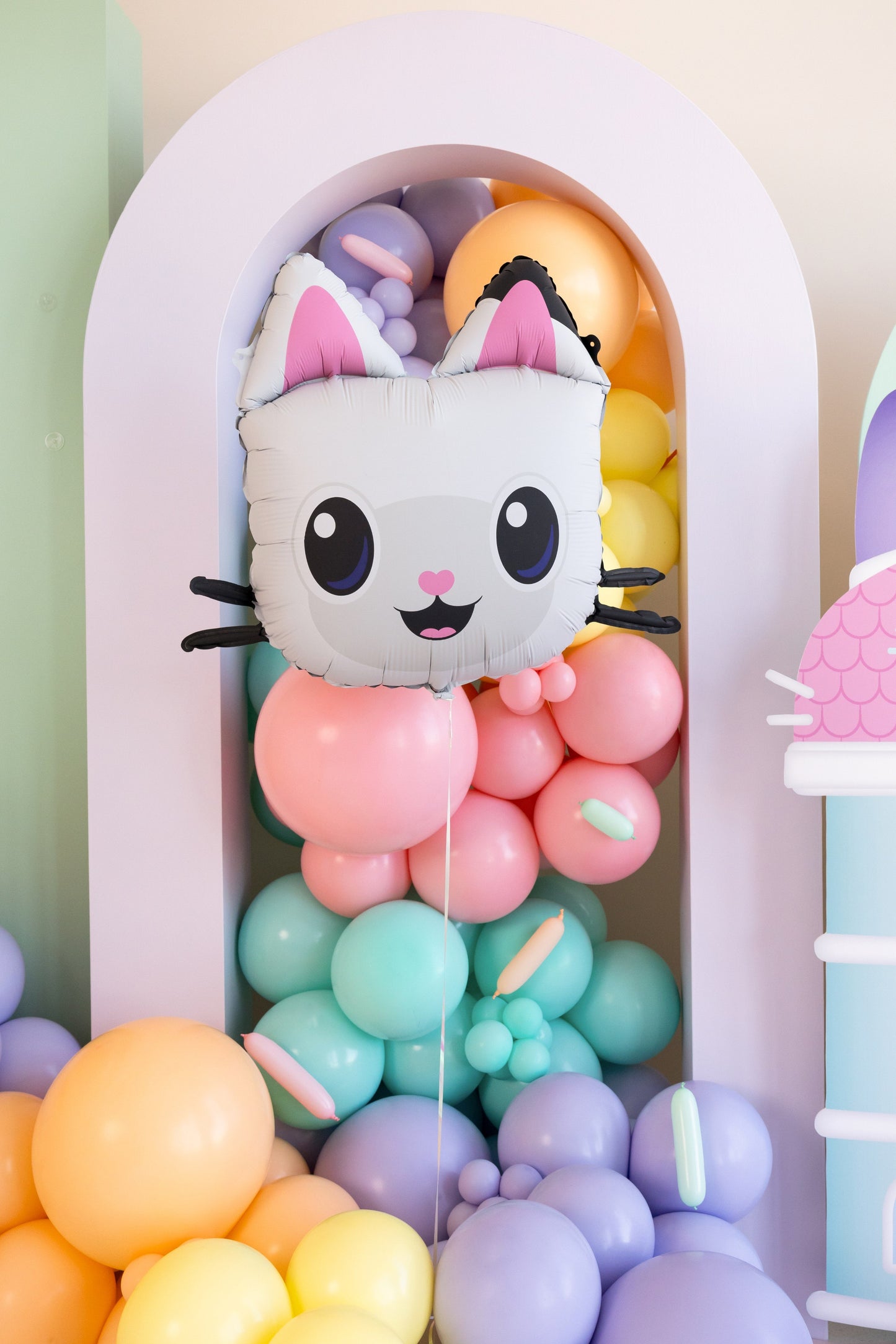 Cute cat-shaped balloon surrounded by colorful balloons in a decorative archway.